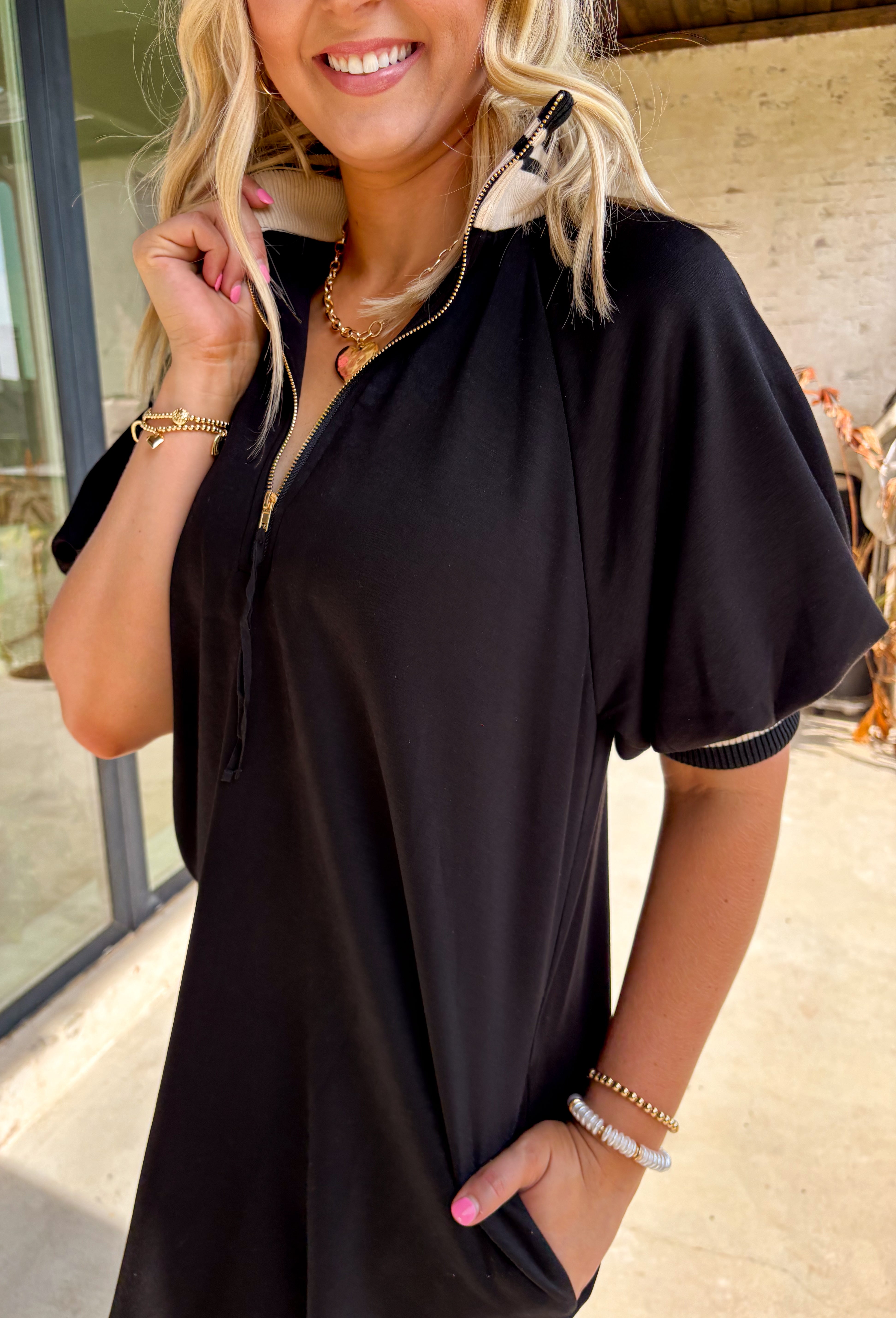 Sporty meets chic in this buttery soft black dress. Designed with a functional front zipper, it’s detailed with multicolor neutral ribbed trim that gives it a laid-back yet polished vibe. Side pockets make it as practical as it is stylish, and the soft, stretchy fabric ensures all-day comfort. Perfect for casual days out or dressed up with accessories for a more elevated look, this one-and-done piece is a true fall staple.