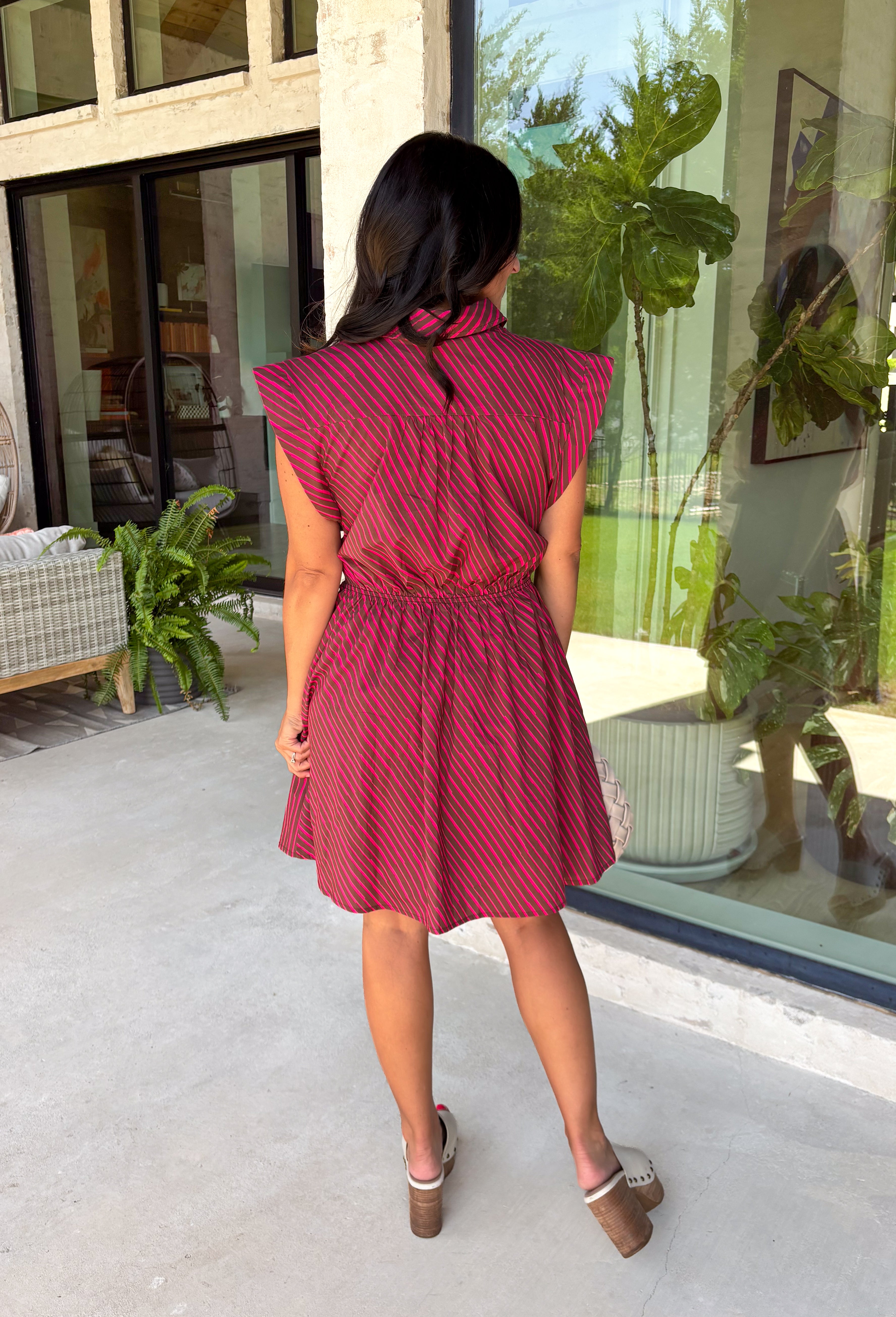This striped dress brings together rich autumn colors and timeless style for a look you'll love all season long. Featuring brown and vibrant fuchsia stripes, it adds a fun pop of color while still feeling perfectly fall-ready. The front button closure and flattering waist tie create a polished silhouette, while the elastic back waist offers a comfortable fit you'll appreciate from morning to night. Finished with cap sleeves, side pockets, and a fully lined design.
