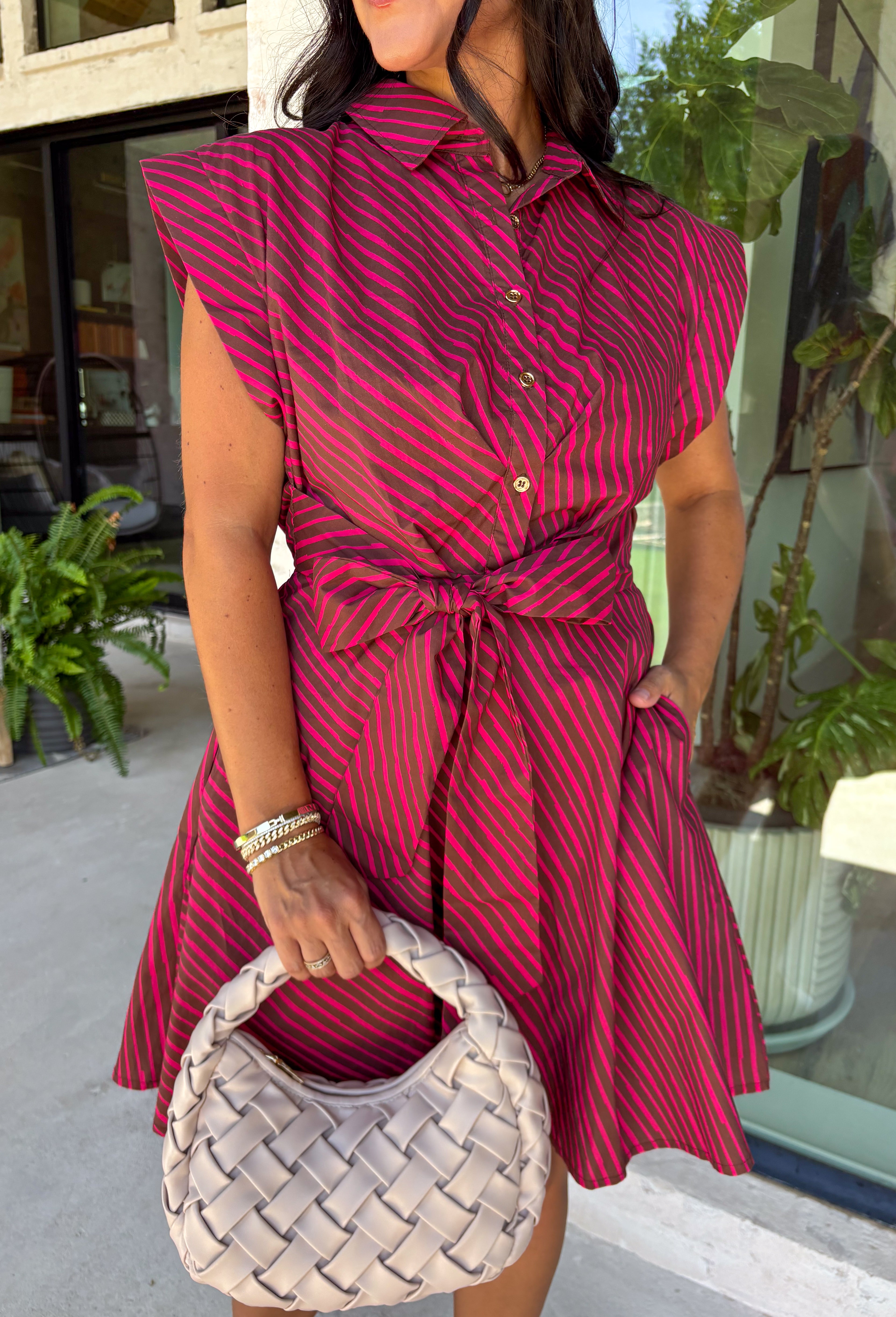 This striped dress brings together rich autumn colors and timeless style for a look you'll love all season long. Featuring brown and vibrant fuchsia stripes, it adds a fun pop of color while still feeling perfectly fall-ready. The front button closure and flattering waist tie create a polished silhouette, while the elastic back waist offers a comfortable fit you'll appreciate from morning to night. Finished with cap sleeves, side pockets, and a fully lined design.