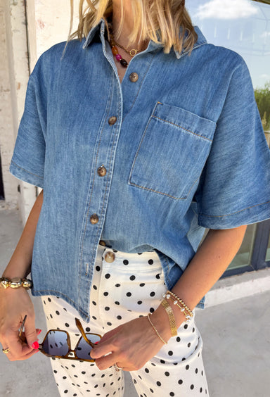 A timeless denim shirt is a wardrobe essential, and this one is designed to go with everything. Crafted from soft medium wash denim with warm tan contrast stitching throughout, this classic button-down top offers effortless style for every season. The collared neckline and front pocket give it a timeless look, while the short sleeves make it perfect for layering or wearing on its own. 