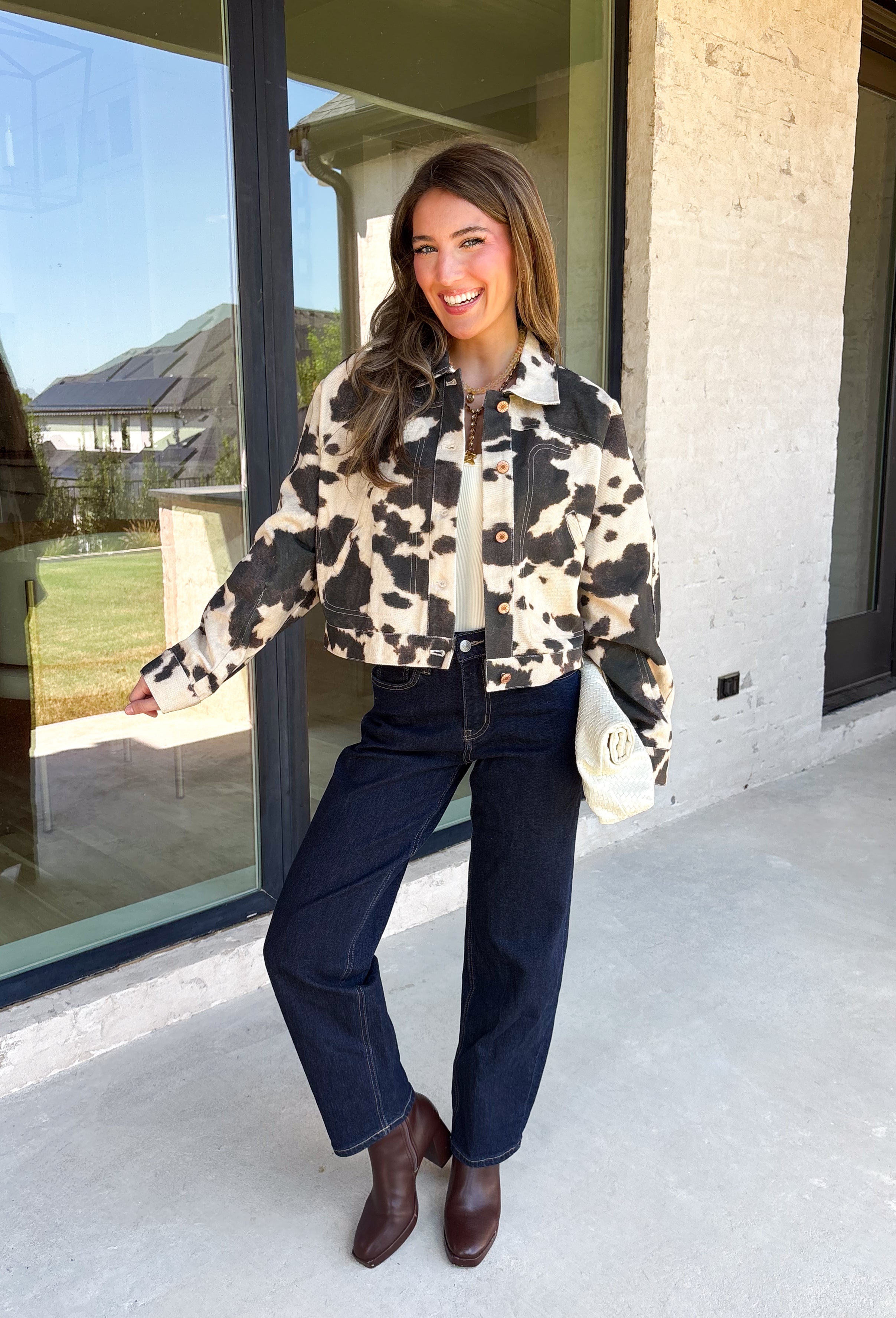 Add a little western-inspired flair to your layering collection with this standout denim jacket from Entro. Designed with a striking cream and black cowhide-inspired print, this timeless piece brings the perfect mix of classic denim styling and bold personality. The collared neckline and button-front closure create a polished, everyday look, while the front pockets add both style and function.