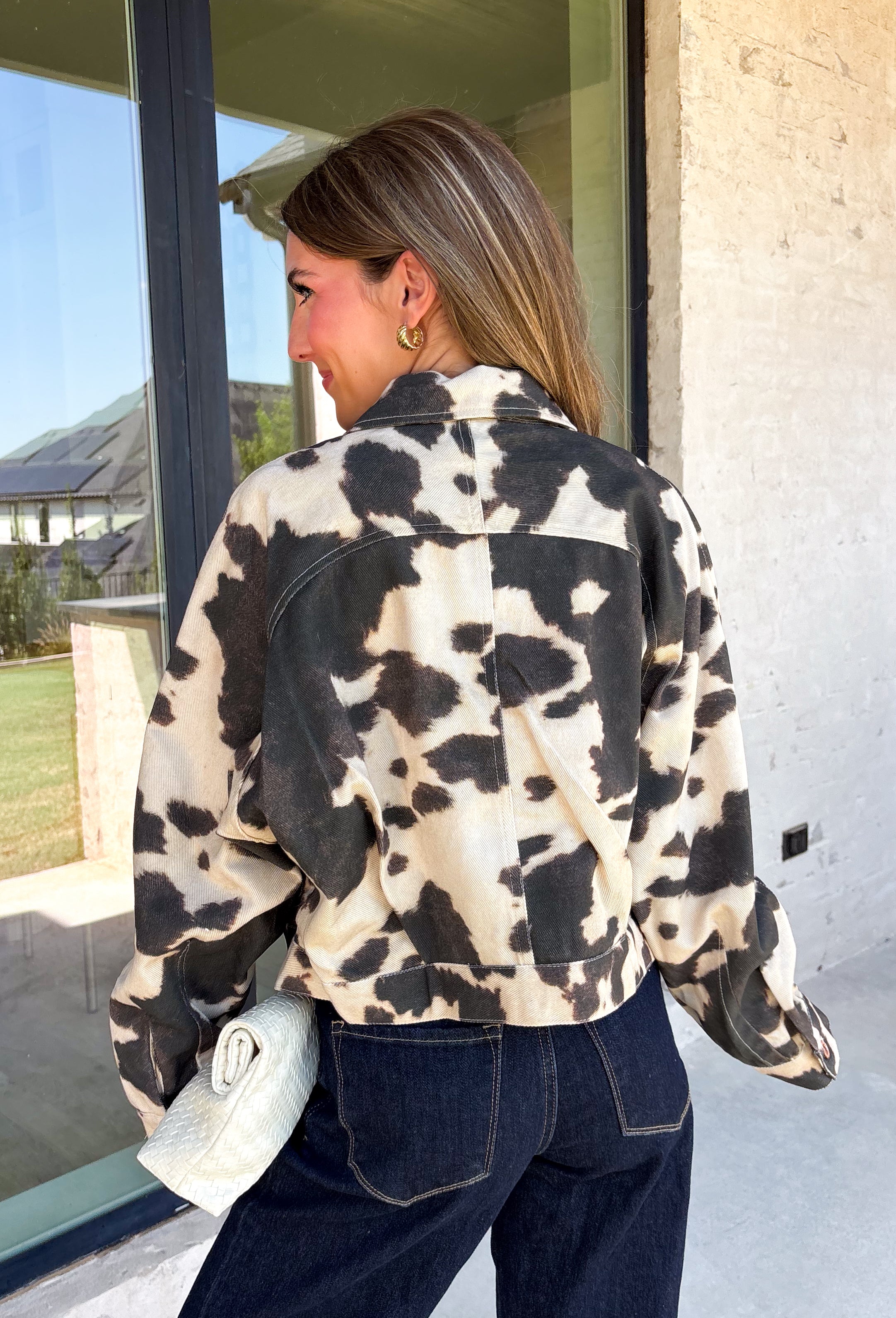 Add a little western-inspired flair to your layering collection with this standout denim jacket from Entro. Designed with a striking cream and black cowhide-inspired print, this timeless piece brings the perfect mix of classic denim styling and bold personality. The collared neckline and button-front closure create a polished, everyday look, while the front pockets add both style and function.