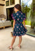 Bright, breezy, and made for spring plans, this navy dress by Entro is full of fun, feel-good color. Featuring a vibrant floral print with pops of purple, pink, green, and blue, it brings the perfect burst of spring energy to a classic navy base. The collared neckline and full button front give it a polished look, while flutter sleeves keep it light and feminine. Finished with contrast scallop trim along the edges, a waist tie for a flattering fit, and side pockets.