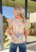 Soft, cheerful, and full of spring color, this cream short sleeve top by Entro is an easy way to brighten your everyday look. Featuring a pretty floral print with pops of green, pink, and coral, it feels light and happy for the season. The coral, white, and green band detail along the front adds a fun contrast, while the coral ruffle neckline gives it a sweet, feminine finish. Made from breathable cotton, this top is perfect for warm spring days.