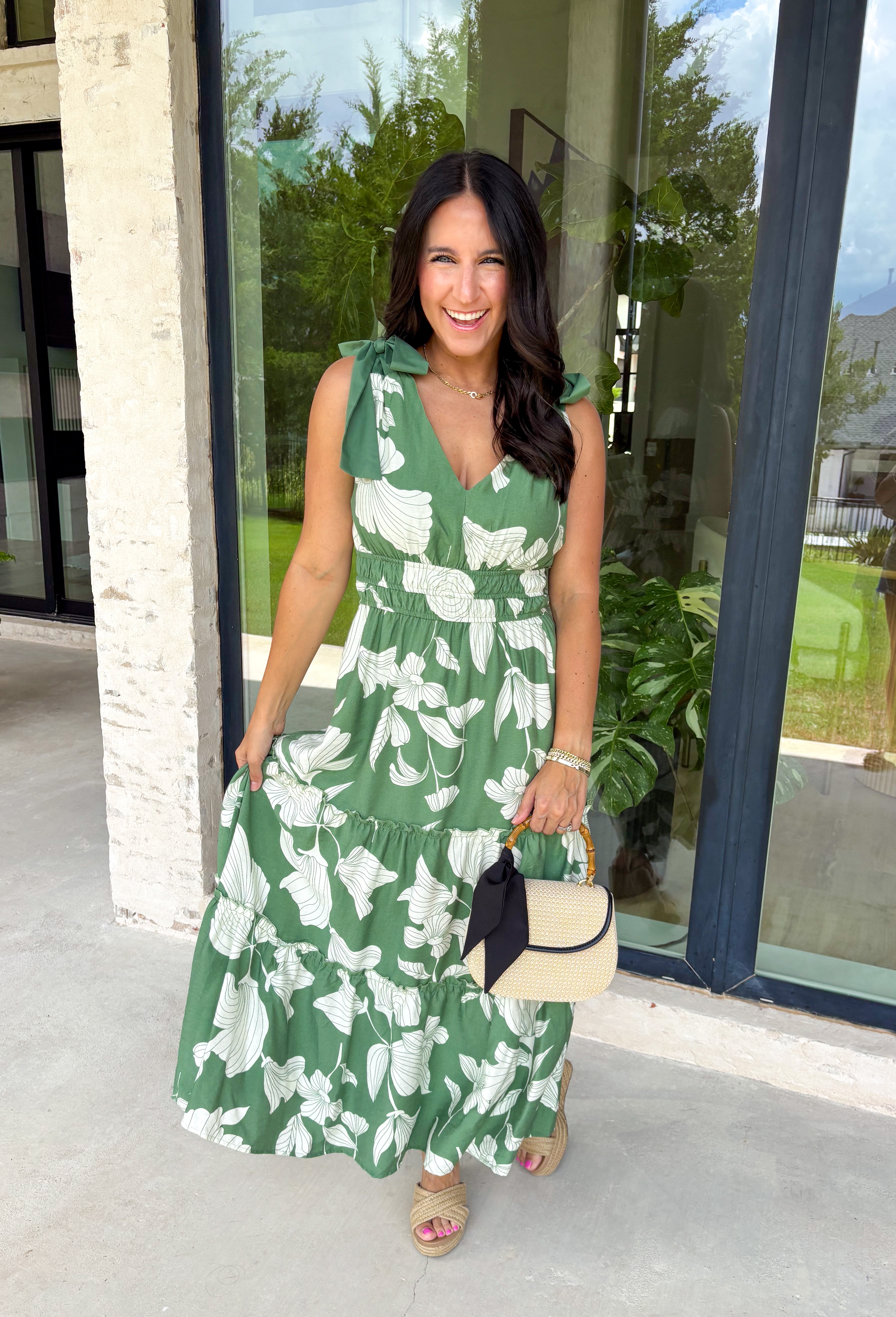 This darker green floral midi dress is such a dreamy, easy piece for summer days! The neutral floral print keeps it soft and wearable, while the tiered ruffle details add beautiful movement and dimension. Designed with adjustable tie straps and an elastic waist, it gives you that flattering, comfortable fit you’ll love all day long. The v-neckline adds a feminine touch, and of course—side pockets make it even better. Fully lined and lightweight, it’s perfect for everything from brunch to vacation dinners. 