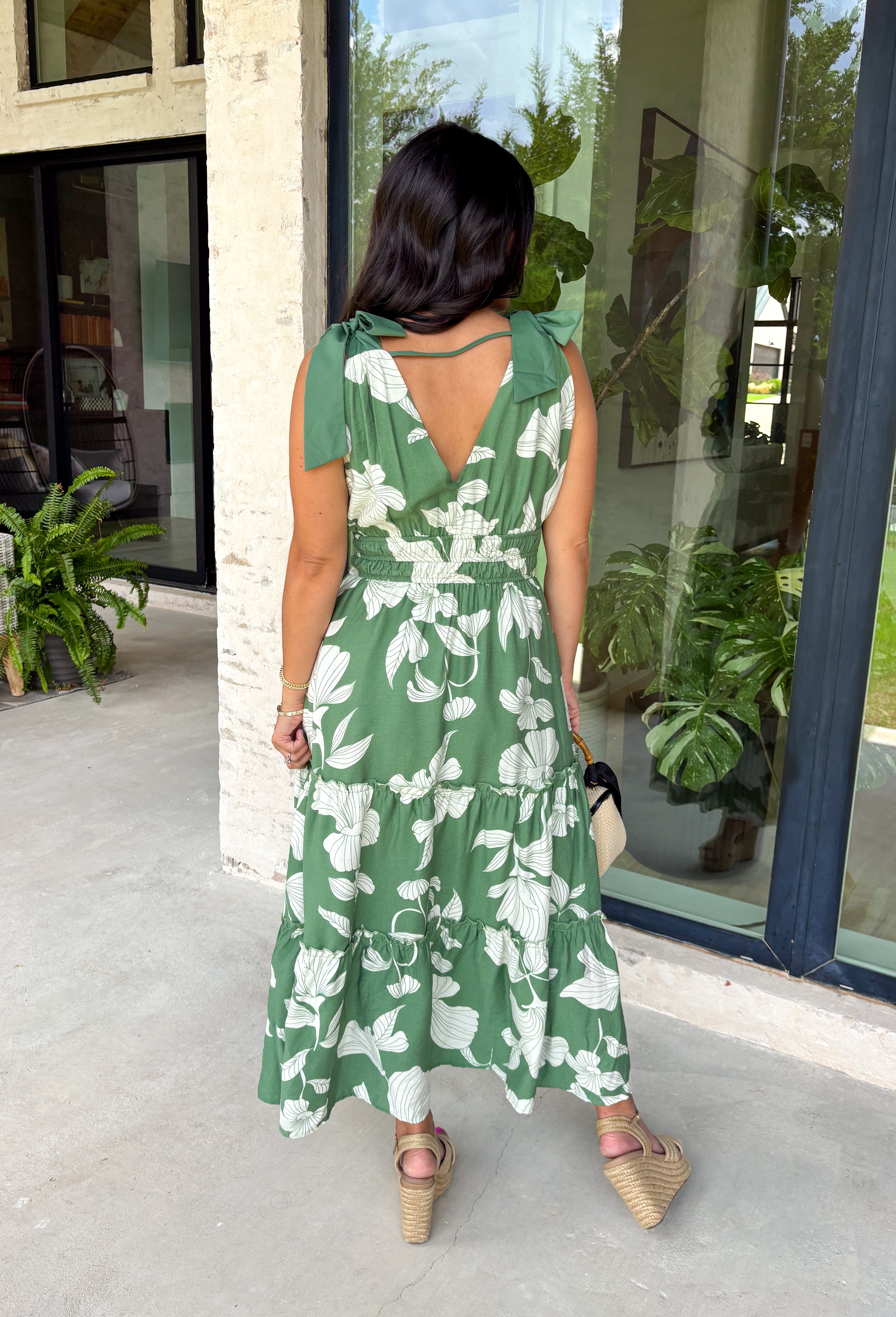 This darker green floral midi dress is such a dreamy, easy piece for summer days! The neutral floral print keeps it soft and wearable, while the tiered ruffle details add beautiful movement and dimension. Designed with adjustable tie straps and an elastic waist, it gives you that flattering, comfortable fit you’ll love all day long. The v-neckline adds a feminine touch, and of course—side pockets make it even better. Fully lined and lightweight, it’s perfect for everything from brunch to vacation dinners. 