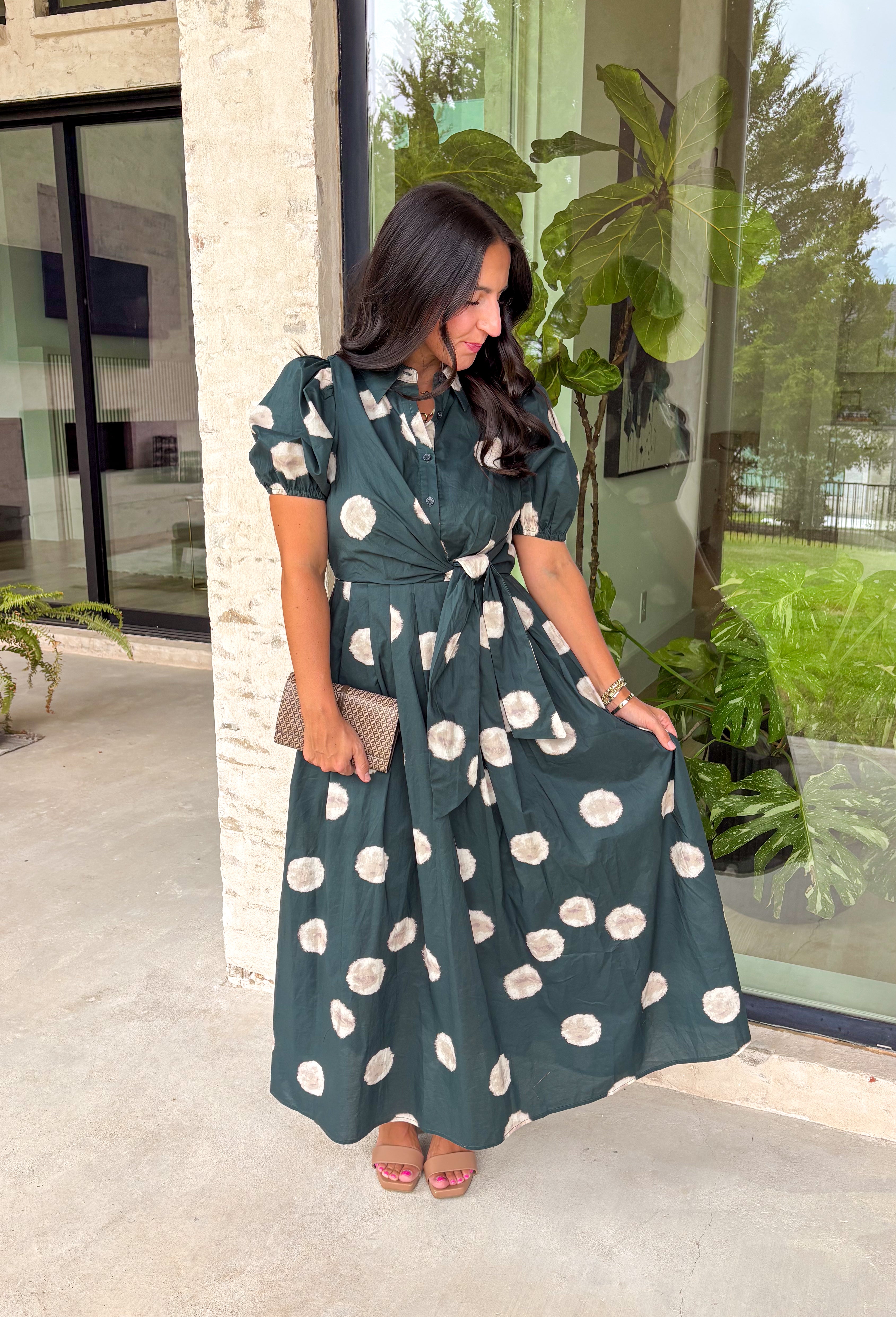 Timeless style meets effortless charm in this beautiful polka dot midi dress. Featuring a rich hunter green backdrop with a bold neutral polka dot print, this classic silhouette is one you'll love wearing year after year. The button-front design and adjustable self-tie waist create a flattering, feminine fit, while the puff sleeves add just the right amount of romantic detail. Complete with side pockets and a fully lined design, this cotton dress is as practical as it is polished.