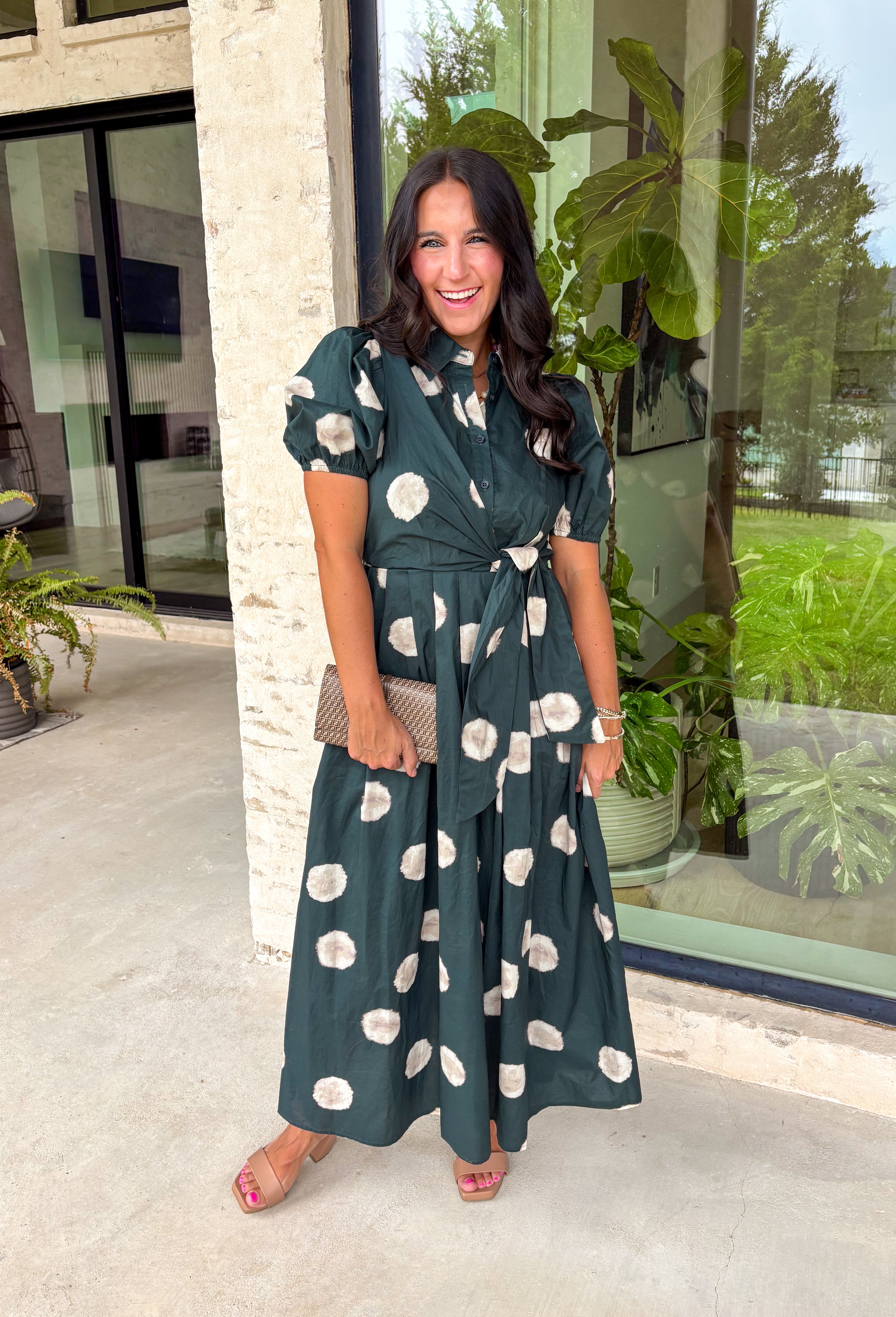 Timeless style meets effortless charm in this beautiful polka dot midi dress. Featuring a rich hunter green backdrop with a bold neutral polka dot print, this classic silhouette is one you'll love wearing year after year. The button-front design and adjustable self-tie waist create a flattering, feminine fit, while the puff sleeves add just the right amount of romantic detail. Complete with side pockets and a fully lined design, this cotton dress is as practical as it is polished.