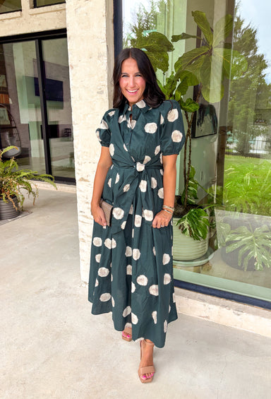 Timeless style meets effortless charm in this beautiful polka dot midi dress. Featuring a rich hunter green backdrop with a bold neutral polka dot print, this classic silhouette is one you'll love wearing year after year. The button-front design and adjustable self-tie waist create a flattering, feminine fit, while the puff sleeves add just the right amount of romantic detail. Complete with side pockets and a fully lined design, this cotton dress is as practical as it is polished.