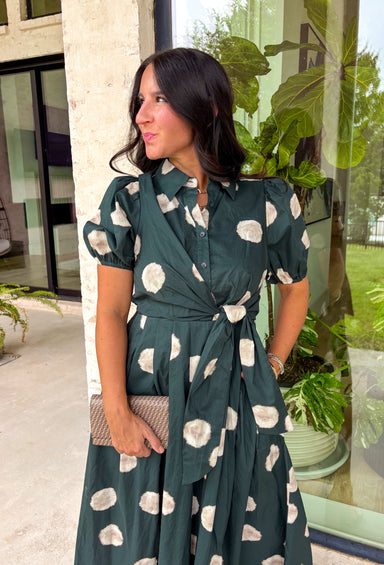 Timeless style meets effortless charm in this beautiful polka dot midi dress. Featuring a rich hunter green backdrop with a bold neutral polka dot print, this classic silhouette is one you'll love wearing year after year. The button-front design and adjustable self-tie waist create a flattering, feminine fit, while the puff sleeves add just the right amount of romantic detail. Complete with side pockets and a fully lined design, this cotton dress is as practical as it is polished.