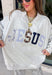 Wear your faith in the coziest way with this heather grey “Jesus” pullover from Bucket List. Each letter features its own unique print, including dainty florals, classic stripes, plaid, and solid navy in a soft mix of neutrals and shades of blue. Light grey embroidery outlines each letter for an extra touch of texture that makes the design stand out beautifully against the heather grey background. 