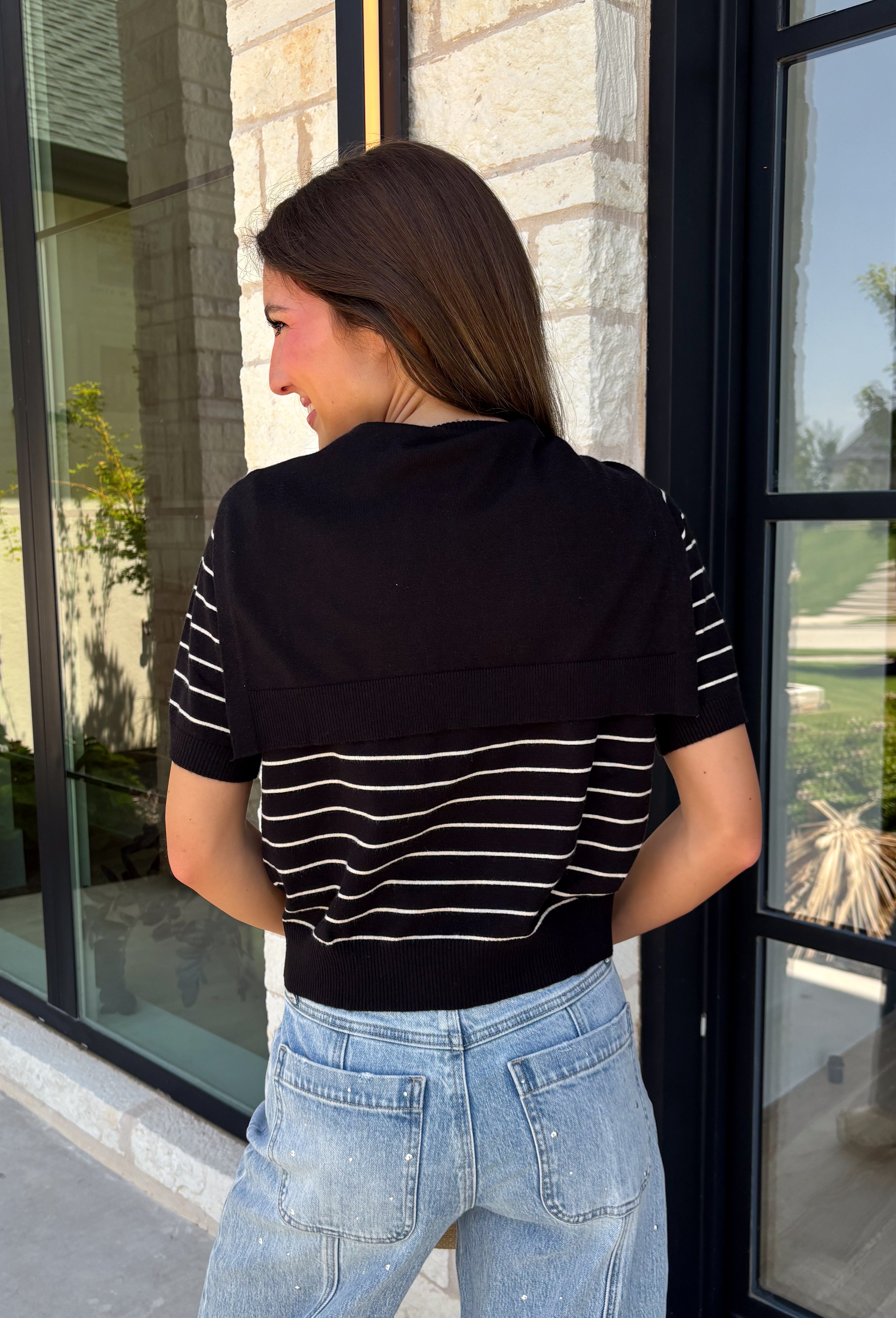 Get the layered look without the extra effort in this cozy short sleeve sweater. Featuring classic black and off white stripes, this knit is designed with an attached layered scarf detail that instantly elevates your outfit. The soft sweater knit keeps you cozy while the short sleeves make it perfect for transitioning through the season and layering under your favorite jackets. Finished with ribbed trim along the neckline, sleeves, and hem.