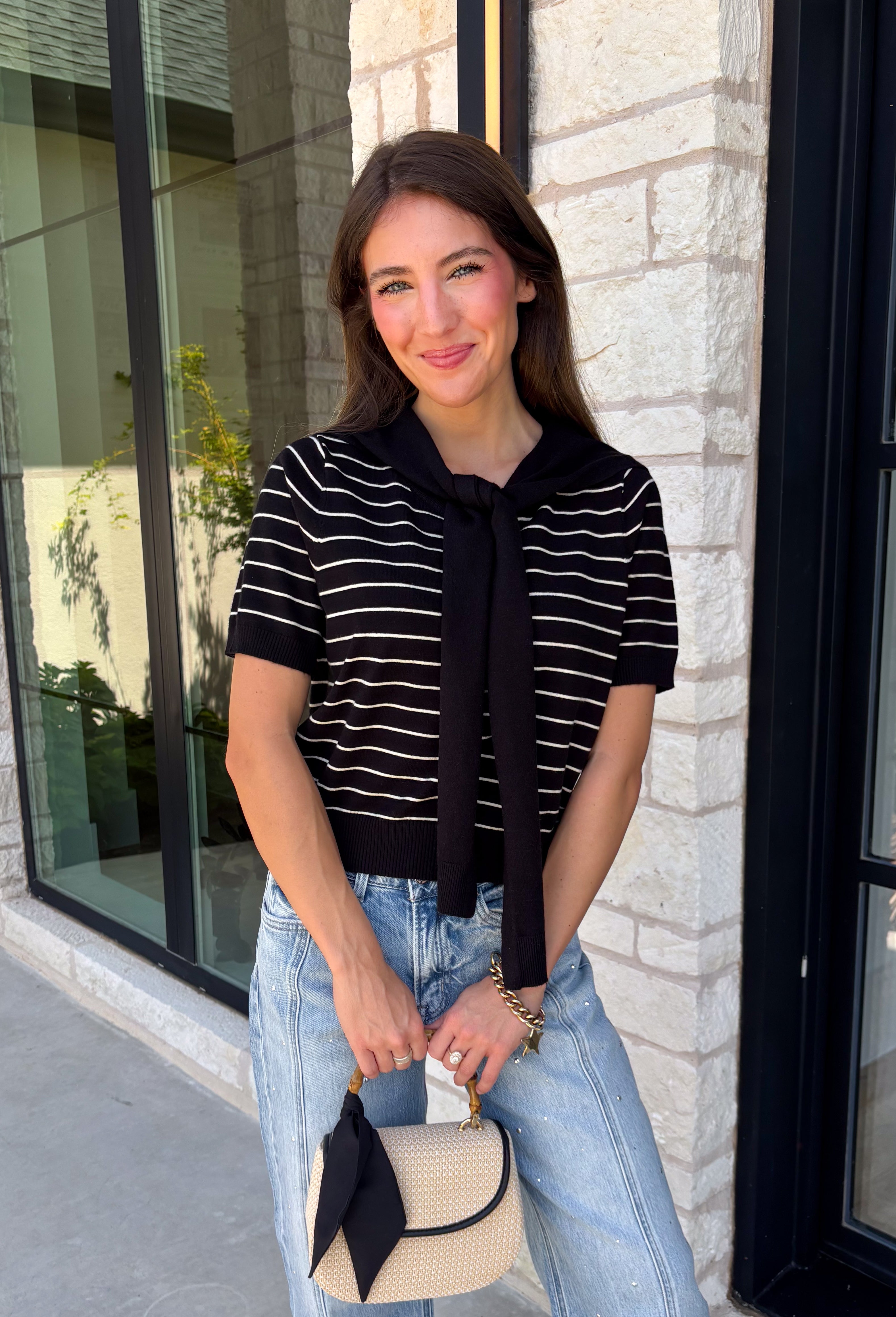 Get the layered look without the extra effort in this cozy short sleeve sweater. Featuring classic black and off white stripes, this knit is designed with an attached layered scarf detail that instantly elevates your outfit. The soft sweater knit keeps you cozy while the short sleeves make it perfect for transitioning through the season and layering under your favorite jackets. Finished with ribbed trim along the neckline, sleeves, and hem.