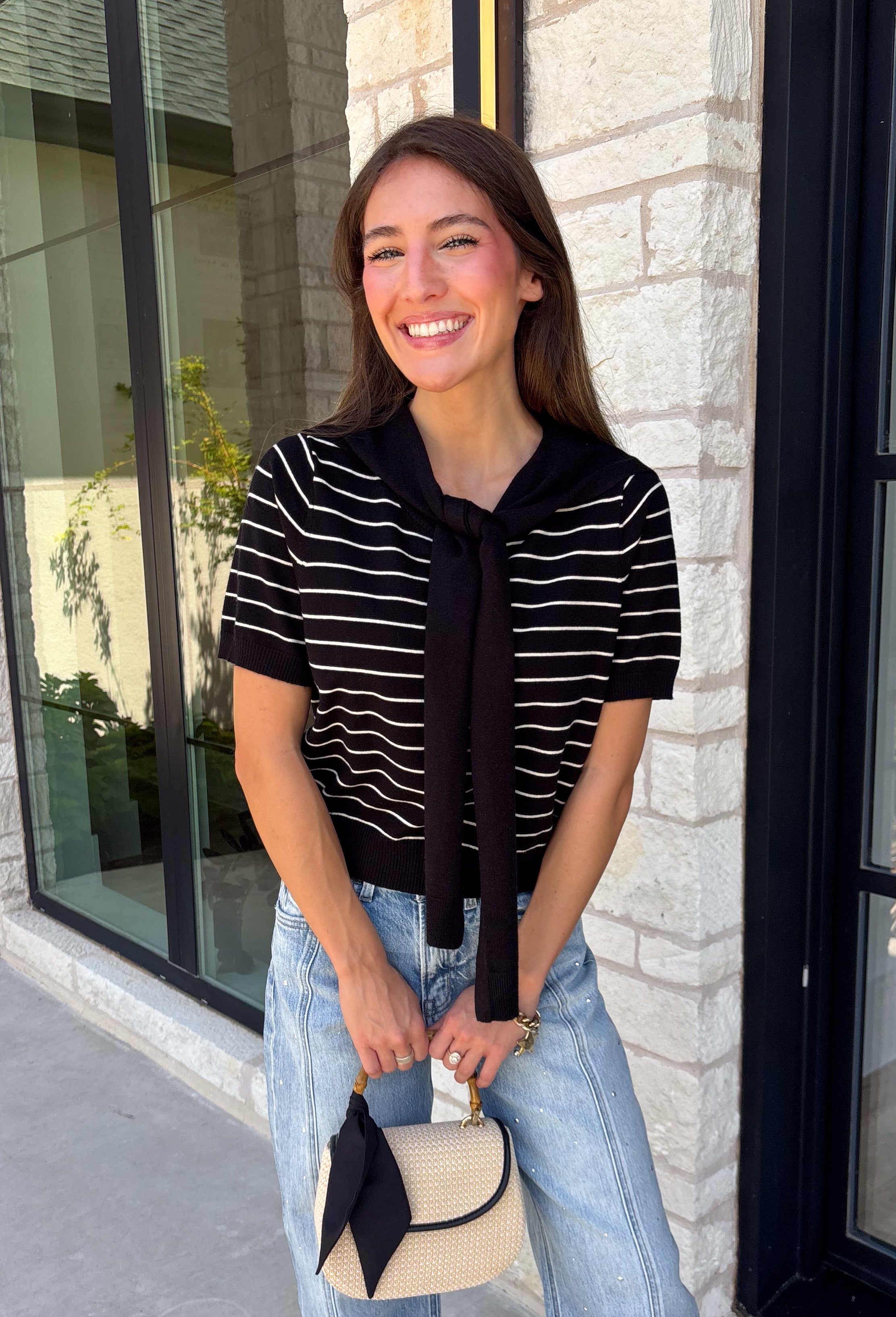Get the layered look without the extra effort in this cozy short sleeve sweater. Featuring classic black and off white stripes, this knit is designed with an attached layered scarf detail that instantly elevates your outfit. The soft sweater knit keeps you cozy while the short sleeves make it perfect for transitioning through the season and layering under your favorite jackets. Finished with ribbed trim along the neckline, sleeves, and hem.
