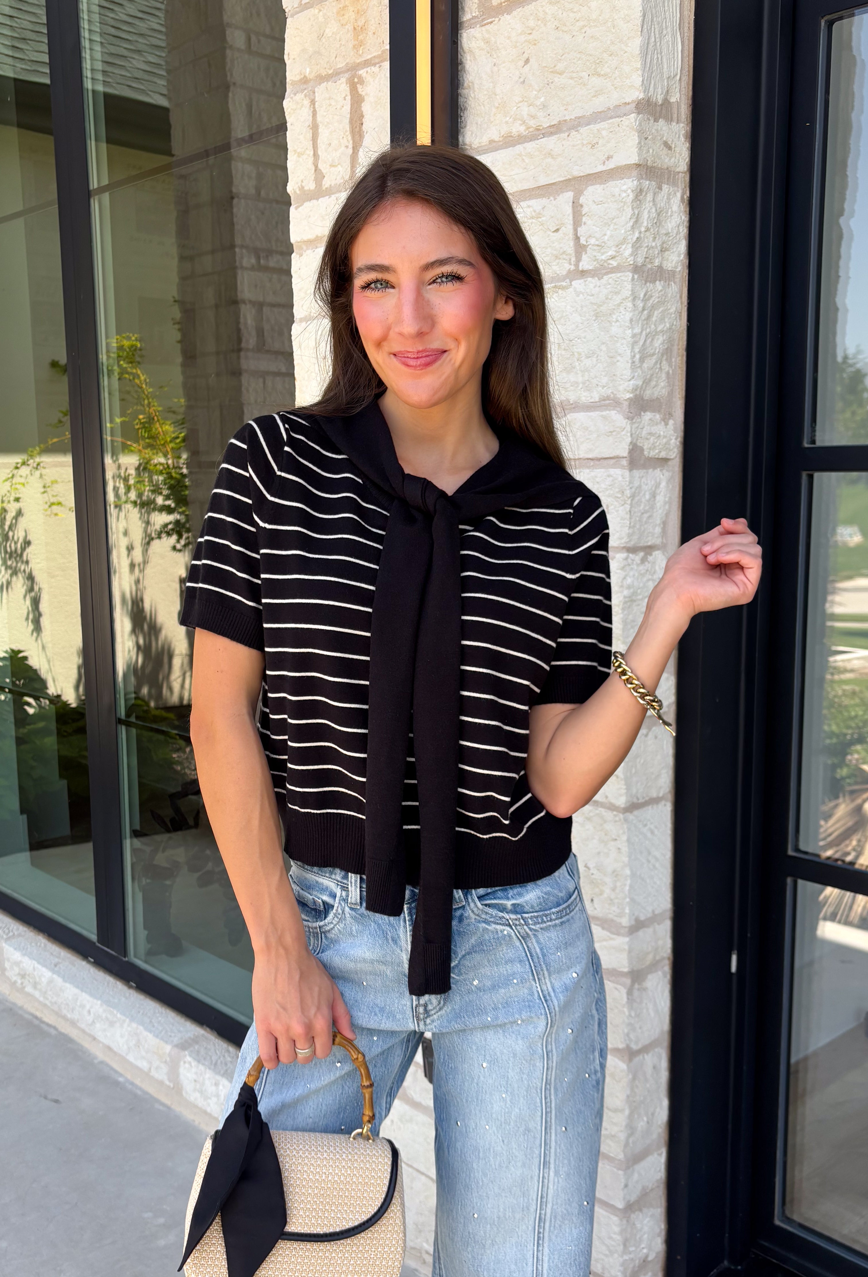 Get the layered look without the extra effort in this cozy short sleeve sweater. Featuring classic black and off white stripes, this knit is designed with an attached layered scarf detail that instantly elevates your outfit. The soft sweater knit keeps you cozy while the short sleeves make it perfect for transitioning through the season and layering under your favorite jackets. Finished with ribbed trim along the neckline, sleeves, and hem.