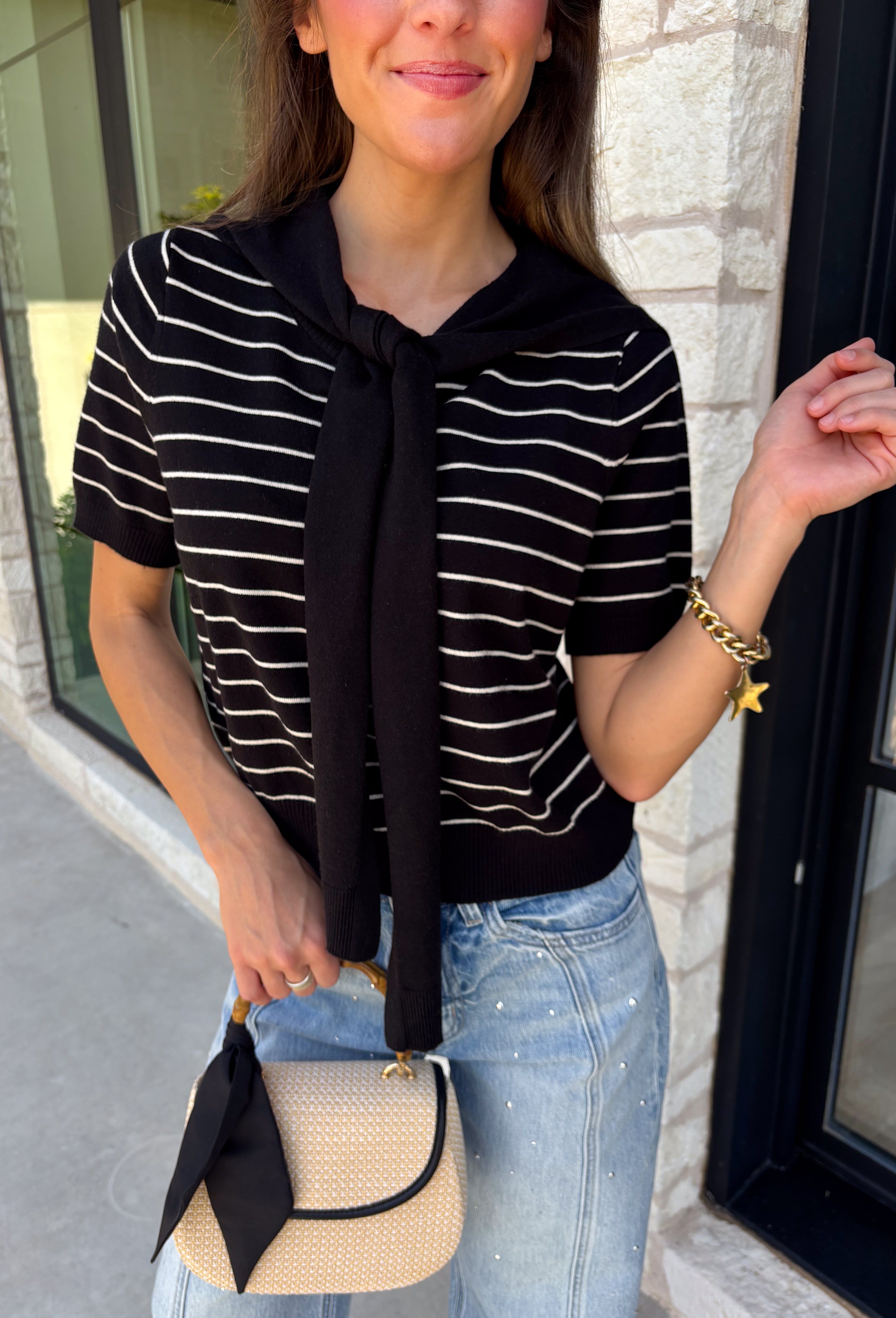 Get the layered look without the extra effort in this cozy short sleeve sweater. Featuring classic black and off white stripes, this knit is designed with an attached layered scarf detail that instantly elevates your outfit. The soft sweater knit keeps you cozy while the short sleeves make it perfect for transitioning through the season and layering under your favorite jackets. Finished with ribbed trim along the neckline, sleeves, and hem.