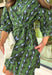 Fresh color meets effortless style in this beautifully designed dress from Entro. Featuring a soft light blue backdrop with a striking hunter green abstract print, this timeless dress is perfect for transitioning through the season. The collared neckline and button-front design create a polished, classic look, while the matching self-tie belt cinches the waist for a flattering silhouette. 