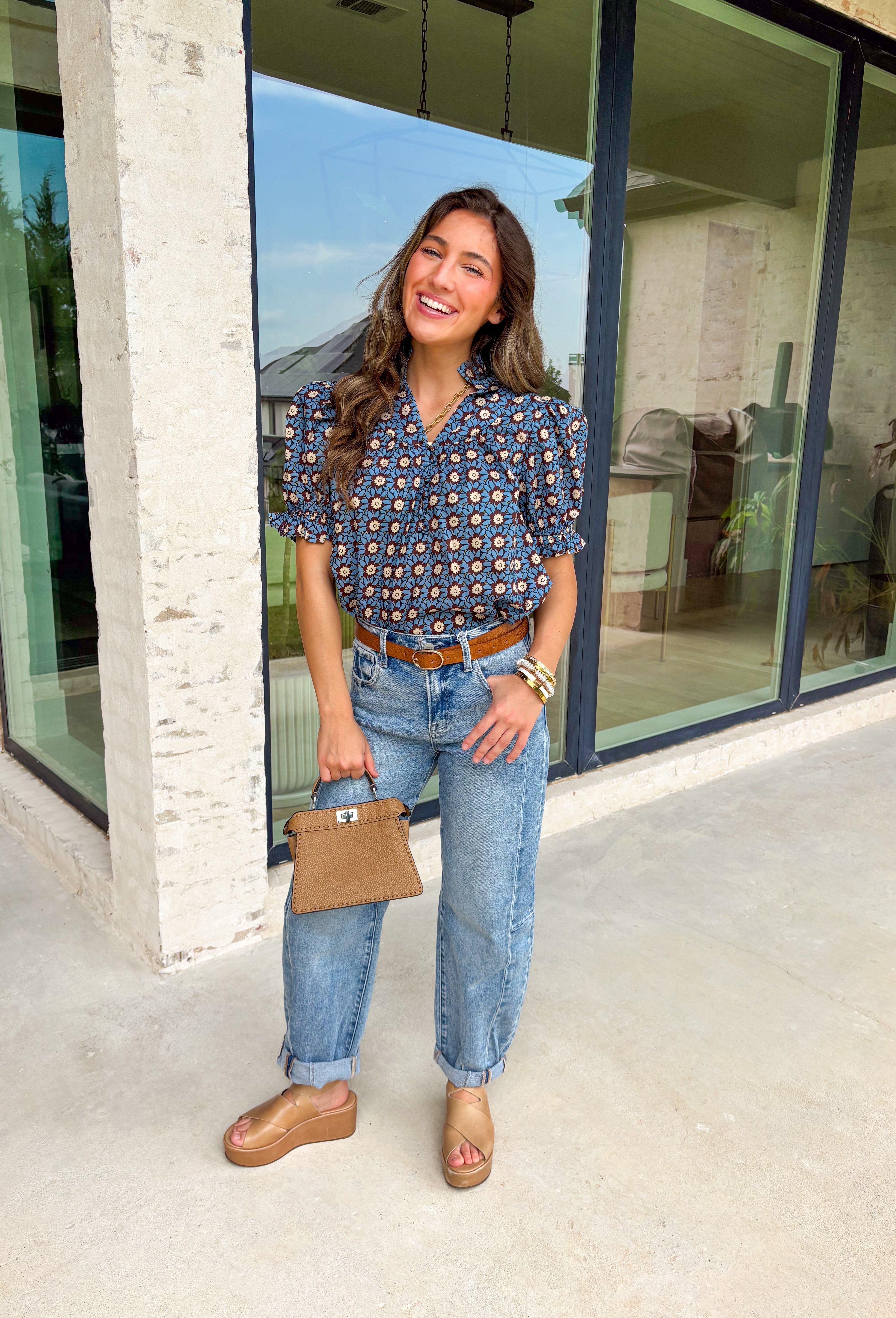 Fall florals have never looked so pretty! This ruffle edge puff sleeve top brings a cozy autumn vibe with its rich brown background and dreamy blue floral print. Whether you're heading to brunch or layering it under a jacket for a pumpkin patch moment, this one's an effortless favorite.