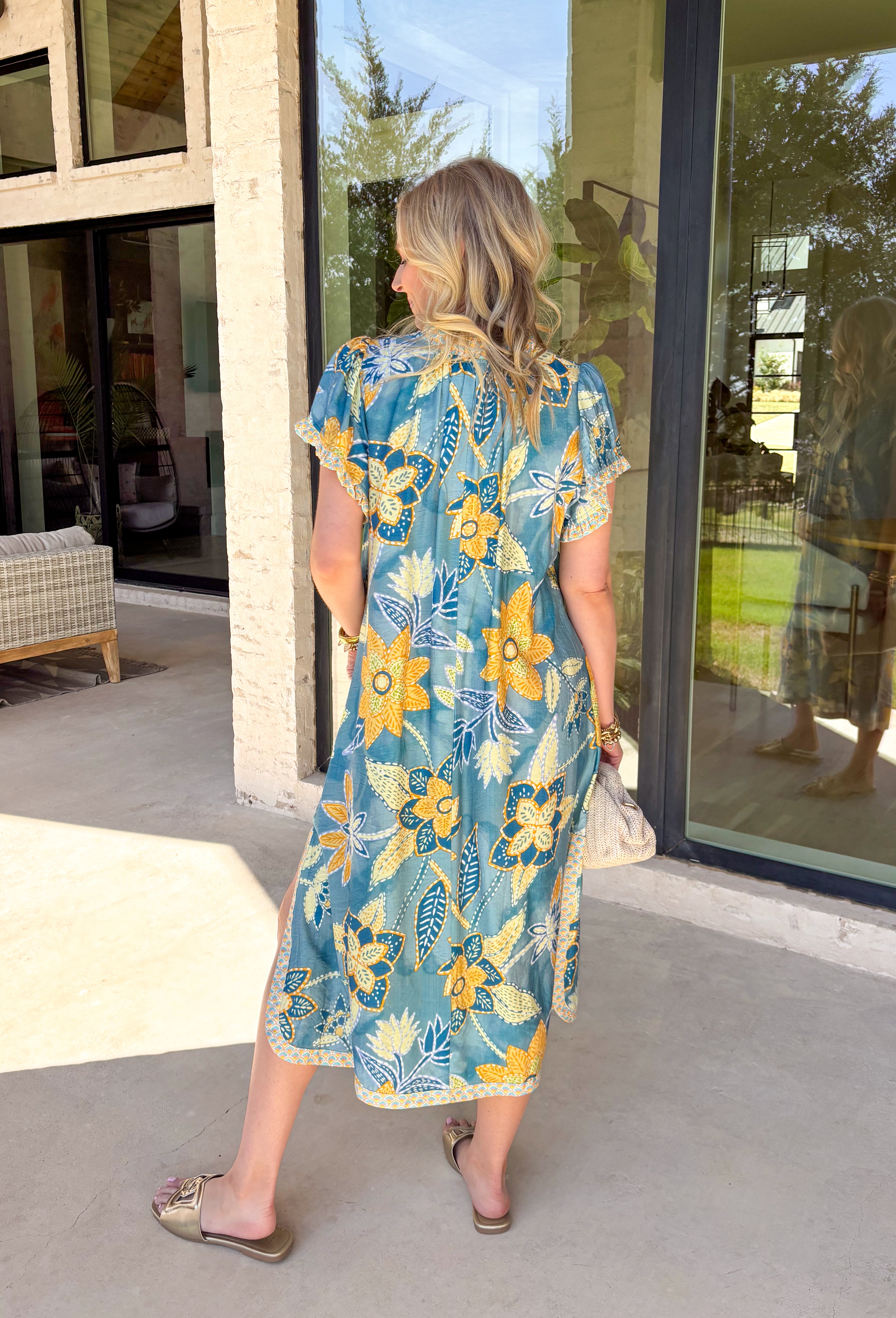 Bold, bright, and full of personality — this blue midi dress is made to stand out. The colorful floral print features shades of yellow, green, blue, and white, giving it that fresh, sunshine-ready feel. What makes it extra special? The contrasting abstract print in orange, pink, and blue along the front, sleeves, and hem for a playful pop of color that truly sets it apart. 