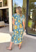 Bold, bright, and full of personality — this blue midi dress is made to stand out. The colorful floral print features shades of yellow, green, blue, and white, giving it that fresh, sunshine-ready feel. What makes it extra special? The contrasting abstract print in orange, pink, and blue along the front, sleeves, and hem for a playful pop of color that truly sets it apart. 