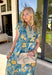 Bold, bright, and full of personality — this blue midi dress is made to stand out. The colorful floral print features shades of yellow, green, blue, and white, giving it that fresh, sunshine-ready feel. What makes it extra special? The contrasting abstract print in orange, pink, and blue along the front, sleeves, and hem for a playful pop of color that truly sets it apart. 