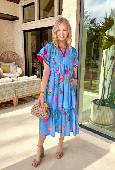 This blue floral midi dress is giving major springtime charm with a fun pop of color! The pink floral print feels bright and cheerful, while the dark pink and turquoise trim along the front and sleeve cuffs adds the cutest contrast detail that makes this dress stand out in the best way. The tiered skirt brings that breezy, twirl-worthy movement we love, and with side pockets + a full lining, it’s just as practical as it is pretty. 