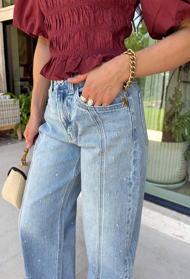 Everyone's favorite barrel jean just got a glamorous upgrade! These high-rise light wash barrel jeans feature crystal and embellishment details throughout, giving a trendy silhouette an eye-catching twist. The flattering high-rise fit helps create a streamlined shape, while the relaxed barrel leg keeps them comfortable and on-trend. Perfect for date nights, concerts, weekend outings, or simply elevating your everyday style, these jeans effortlessly blend casual and chic.