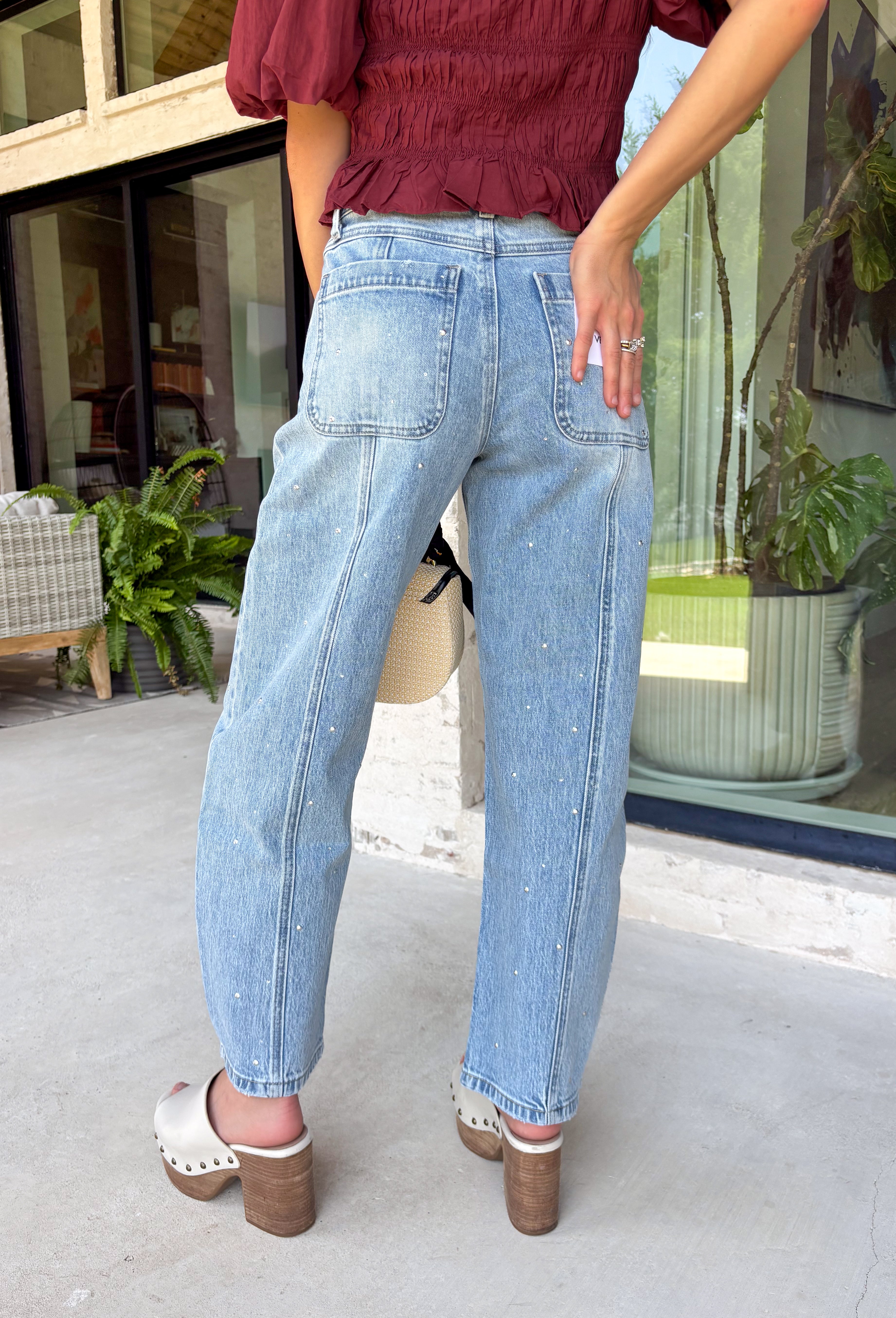 Everyone's favorite barrel jean just got a glamorous upgrade! These high-rise light wash barrel jeans feature crystal and embellishment details throughout, giving a trendy silhouette an eye-catching twist. The flattering high-rise fit helps create a streamlined shape, while the relaxed barrel leg keeps them comfortable and on-trend. Perfect for date nights, concerts, weekend outings, or simply elevating your everyday style, these jeans effortlessly blend casual and chic.