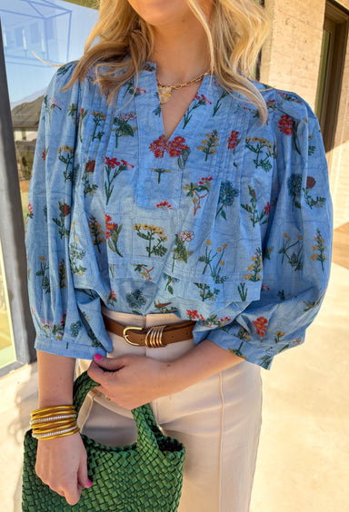 Colorful, lightweight, and full of spring charm, this blue 3/4 sleeve top by Entro is an easy standout for the season. Featuring a patchwork-style floral print in shades of burgundy, green, mustard, and blue, it adds just the right amount of personality to your everyday look. Pleating details at both the front and back give it a flattering drape and comfortable movement, making it as easy to wear as it is pretty.