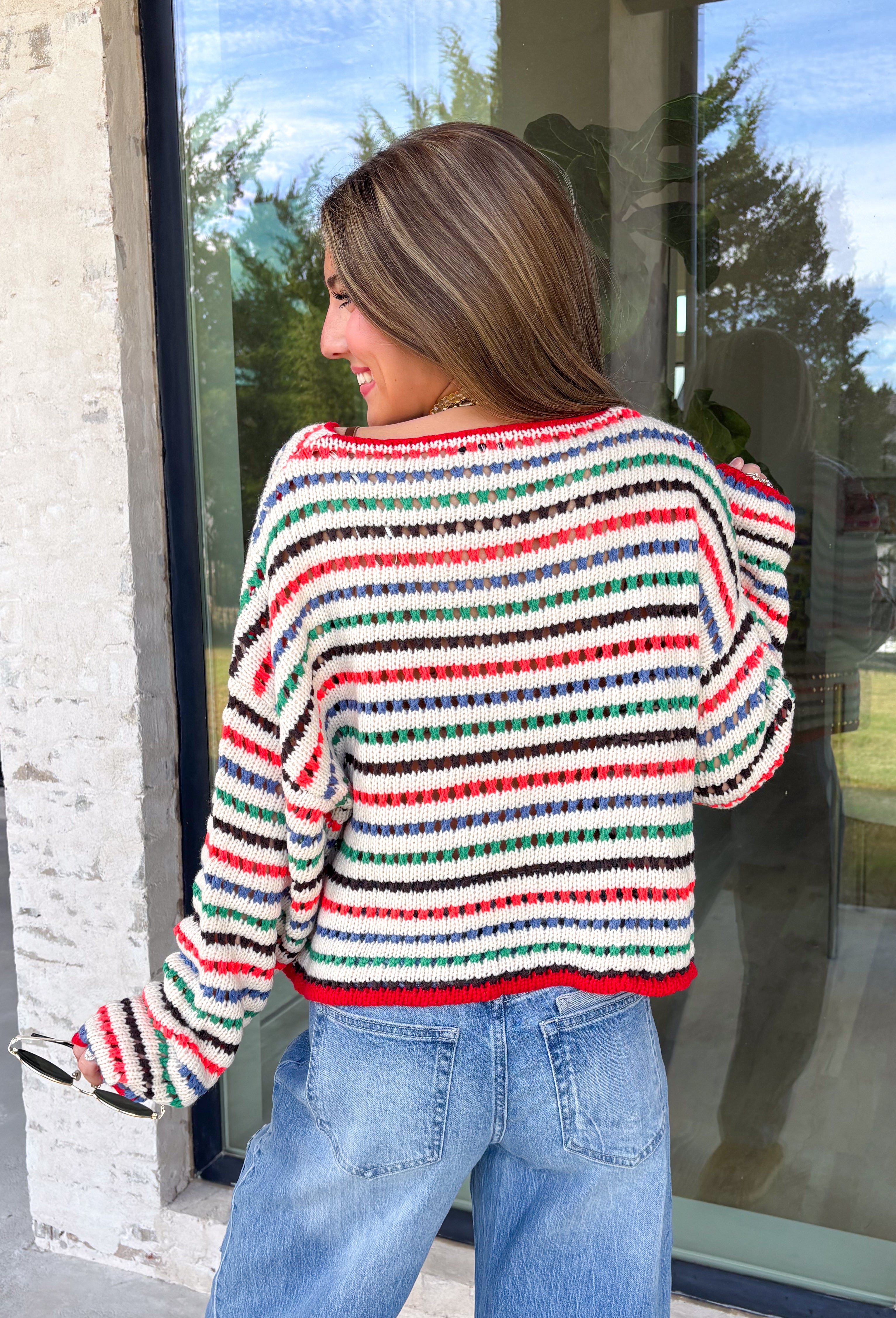 Cozy season gets a colorful update with this cream open knit sweater from Hyfve. The neutral cream base is woven with playful pops of red, blue, green, and black, giving it plenty of personality while still keeping it easy to mix and match. The open knit design creates a textured look that’s perfect for layering as those crisp fall days start turning colder. 