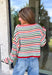 Cozy season gets a colorful update with this cream open knit sweater from Hyfve. The neutral cream base is woven with playful pops of red, blue, green, and black, giving it plenty of personality while still keeping it easy to mix and match. The open knit design creates a textured look that’s perfect for layering as those crisp fall days start turning colder. 