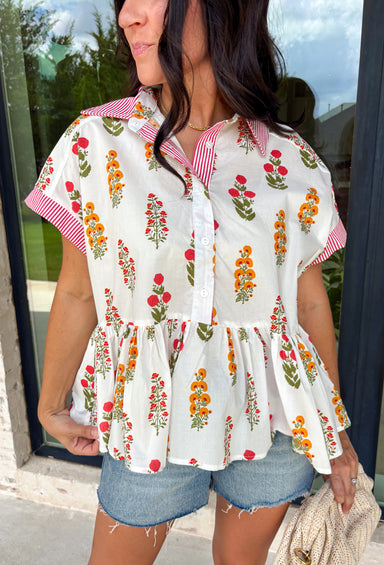 This white babydoll top is the perfect mix of playful and feminine for summer! The colorful floral print in yellow, red, and green brings a bright, happy feel, while the red and white stripe detail on the collar and sleeves adds the cutest pop of contrast. The babydoll silhouette keeps it light, breezy, and easy to wear, and the front button details give it that extra touch of charm. Made from breathable cotton, it’s perfect for warm days when you want something effortless but still fun.