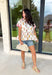 This white babydoll top is the perfect mix of playful and feminine for summer! The colorful floral print in yellow, red, and green brings a bright, happy feel, while the red and white stripe detail on the collar and sleeves adds the cutest pop of contrast. The babydoll silhouette keeps it light, breezy, and easy to wear, and the front button details give it that extra touch of charm. Made from breathable cotton, it’s perfect for warm days when you want something effortless but still fun.