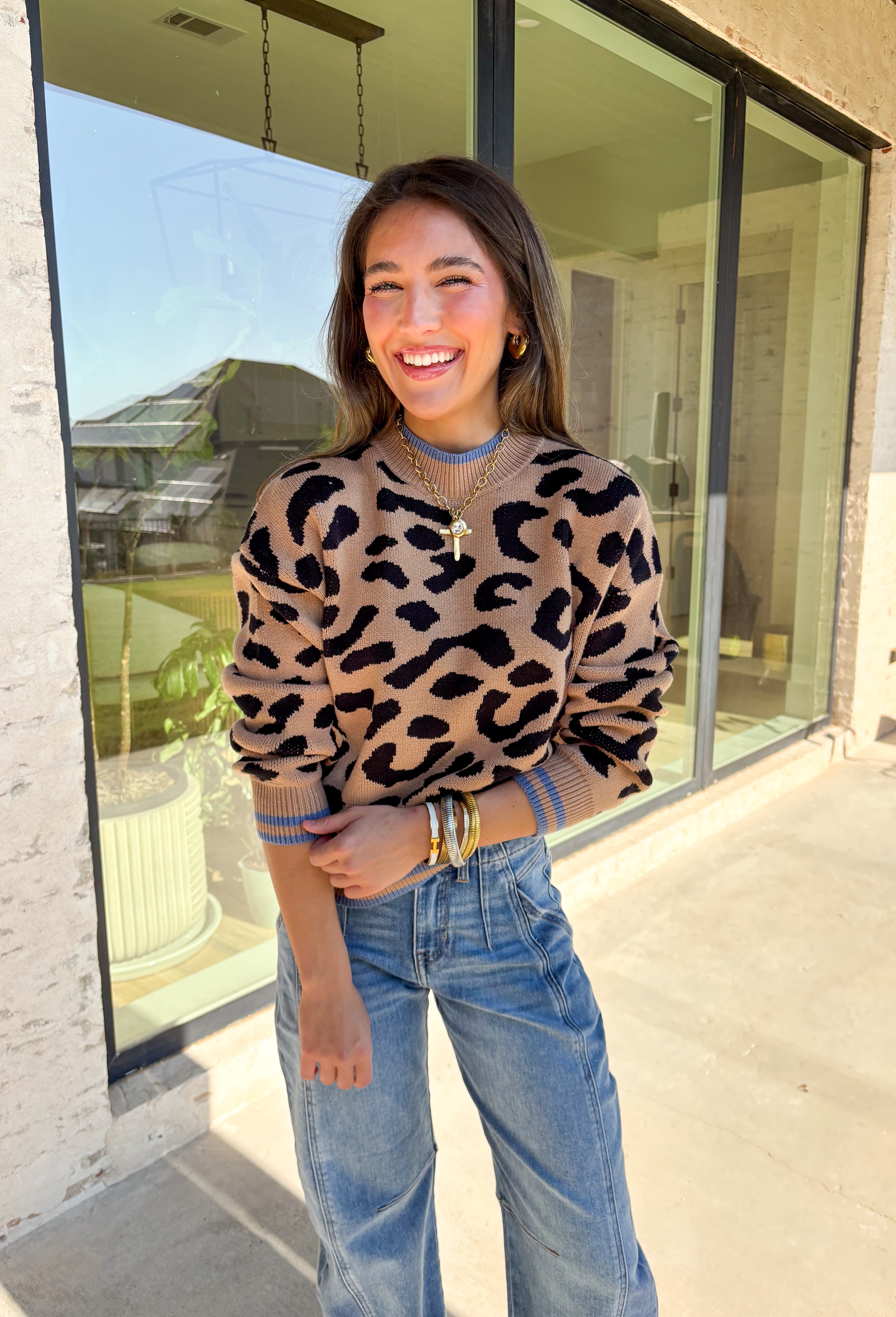 A cozy classic with a playful twist, this tan mock neck sweater is accented with a bold black leopard print. The pop of blue trim along the neckline, hem, and cuffs brings a modern contrast that sets it apart. Soft and stretchy in a comfy knit blend, it’s perfect for layering with denim, skirts, or trousers. A versatile piece that makes everyday outfits feel just a little more fun this fall.