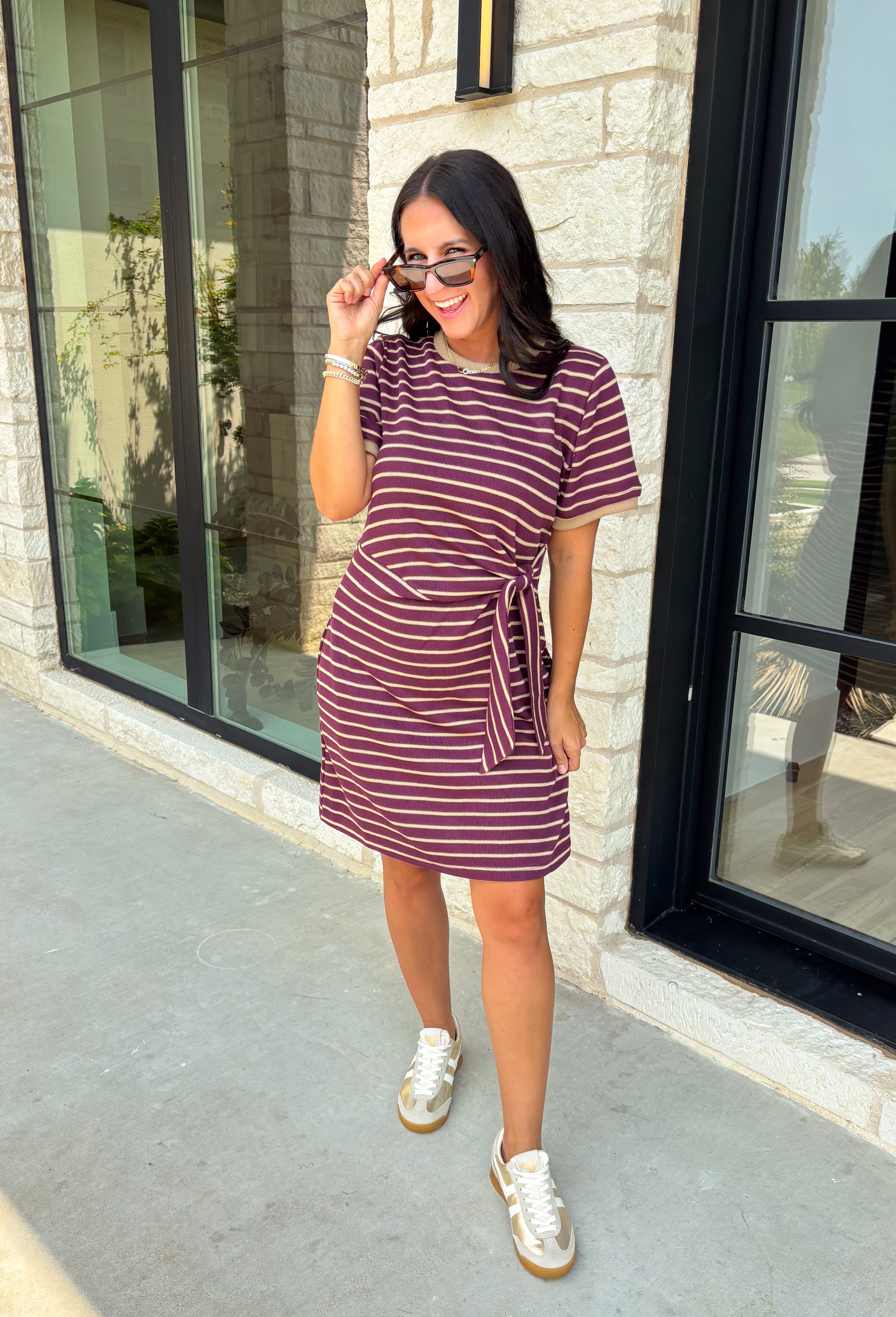 From busy weekdays to weekend plans, this striped dress is the effortless piece you'll find yourself reaching for again and again! Designed with classic plum and tan stripes, this lightweight dress offers the perfect mix of comfort and polished style for the season. The adjustable self-tie waist creates a flattering silhouette, while the contrast ribbed neckline and sleeve cuffs add a sporty-chic touch that makes this dress stand out. 