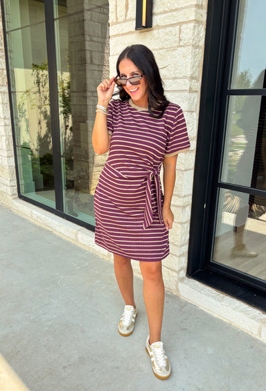 From busy weekdays to weekend plans, this striped dress is the effortless piece you'll find yourself reaching for again and again! Designed with classic plum and tan stripes, this lightweight dress offers the perfect mix of comfort and polished style for the season. The adjustable self-tie waist creates a flattering silhouette, while the contrast ribbed neckline and sleeve cuffs add a sporty-chic touch that makes this dress stand out. 