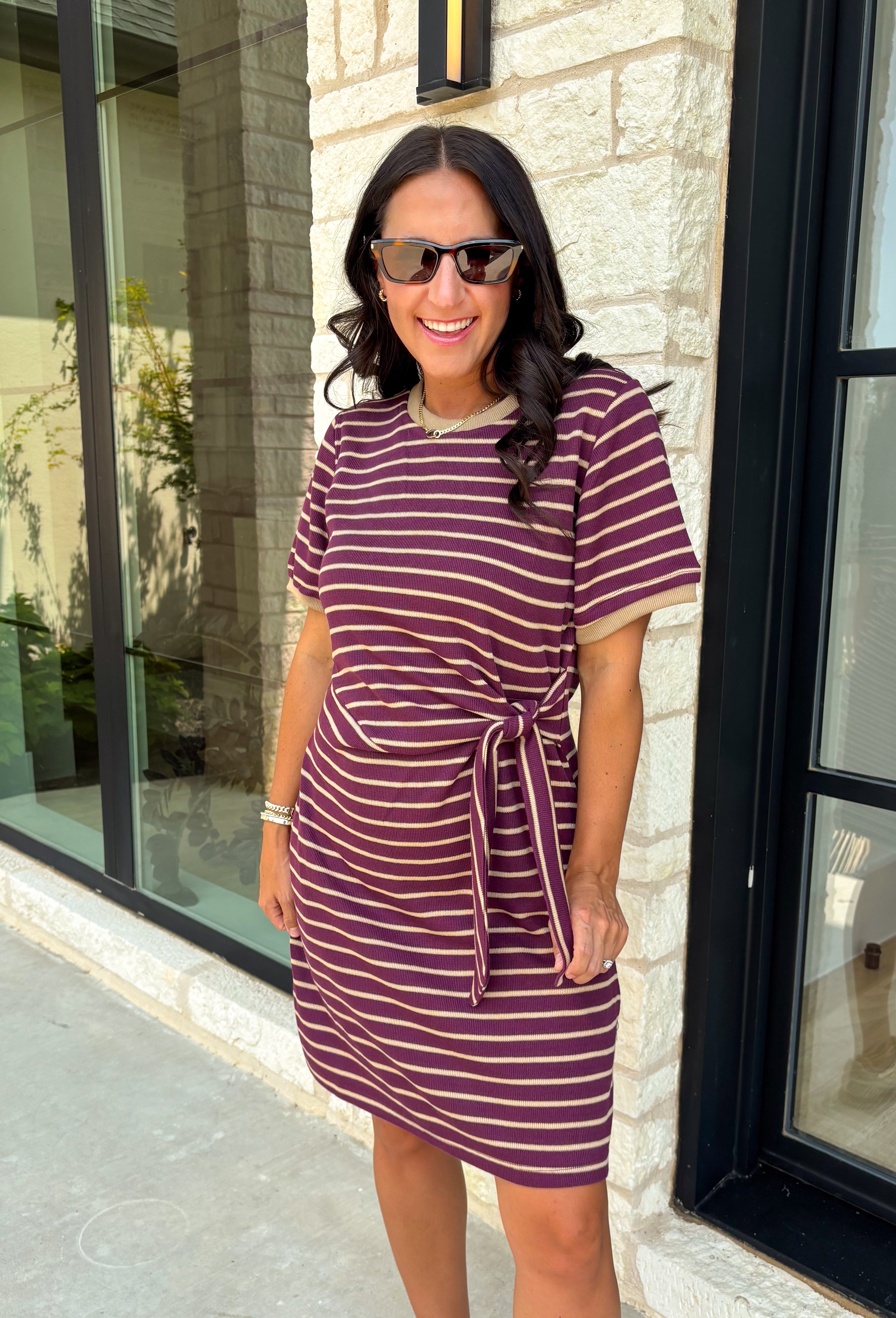 From busy weekdays to weekend plans, this striped dress is the effortless piece you'll find yourself reaching for again and again! Designed with classic plum and tan stripes, this lightweight dress offers the perfect mix of comfort and polished style for the season. The adjustable self-tie waist creates a flattering silhouette, while the contrast ribbed neckline and sleeve cuffs add a sporty-chic touch that makes this dress stand out. 