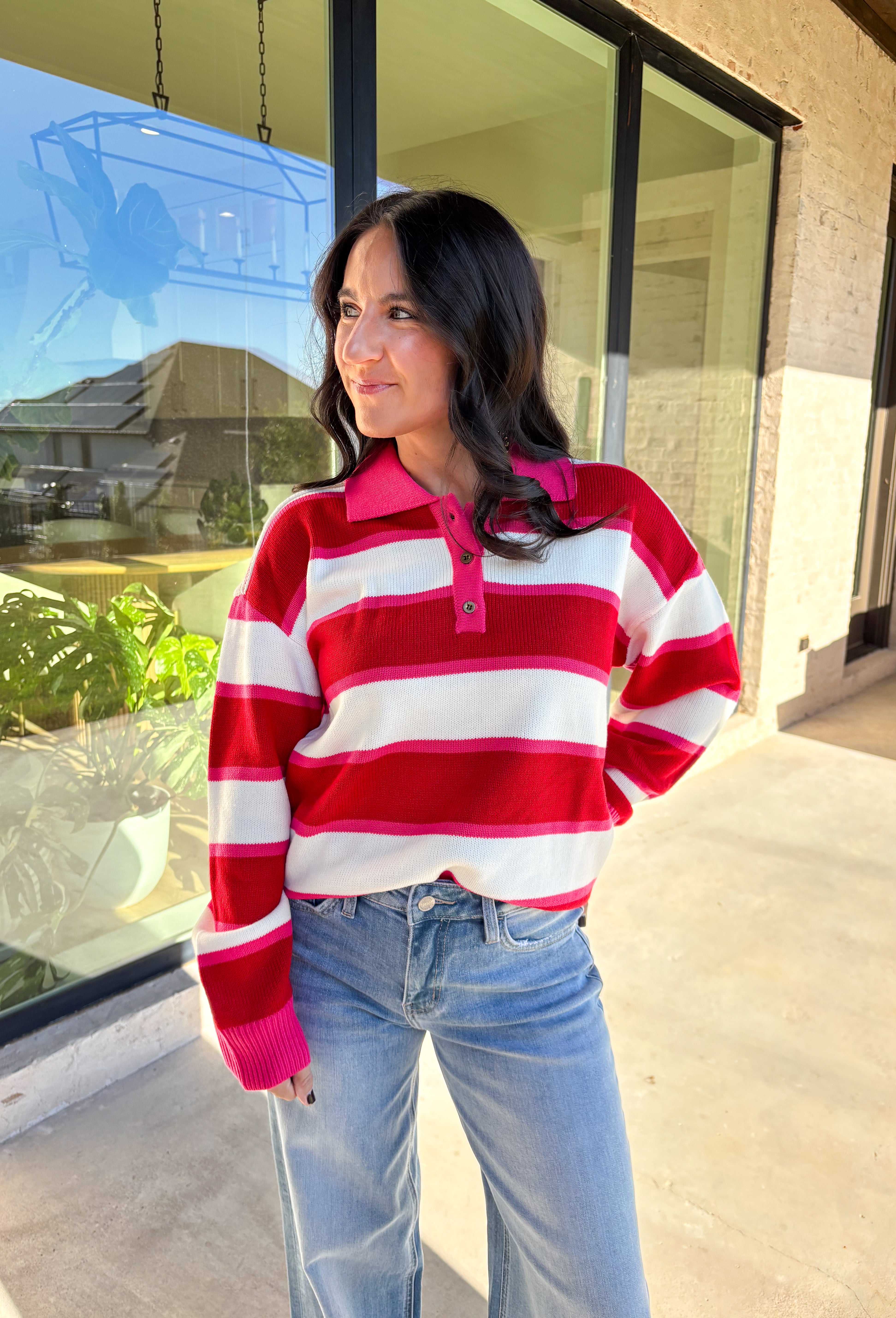 This striped sweater is giving retro prep meets pumpkin spice—and we’re here for it. With bold red, playful pink, and classic white stripes, it brings a cheerful twist to gloomy fall days. The collared neckline and front button details add a polished touch that feels just right for layering over your favorite jeans or corduroy skirt. Made from soft, cozy acrylic, it’s a lightweight piece that still keeps you warm on crisp autumn mornings. Whether you’re headed to the office or a cider-sipping weekend, this 