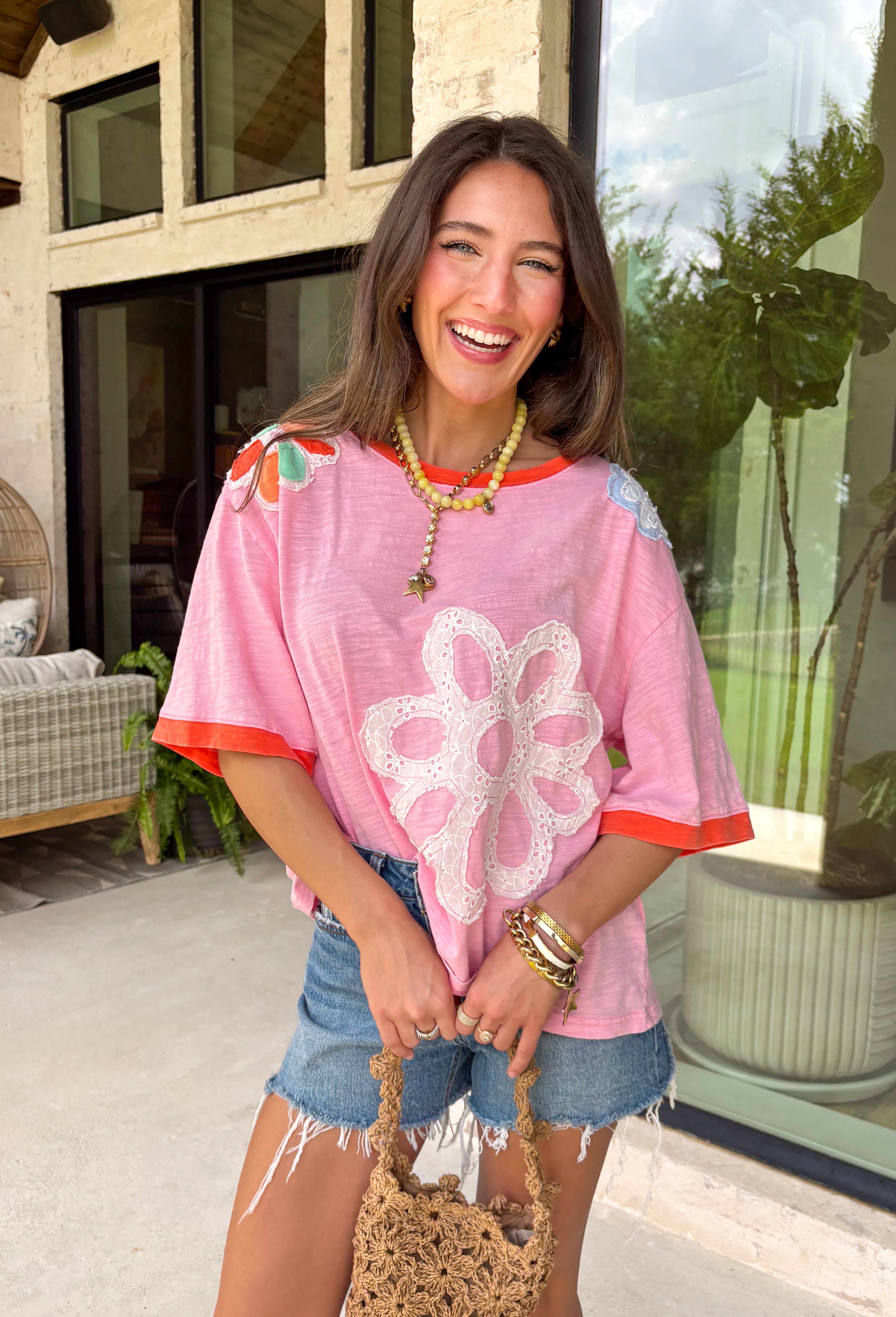 This pink floral top is full of those pretty little details that make summer outfits feel extra special! Featuring a colorful floral print with embroidered accents and white eyelet detailing, it has the perfect mix of texture and charm. The coral trim along the neckline and sleeves adds a fun pop of contrast that really makes it stand out. Lightweight and breathable in 100% cotton, it’s perfect for warm days when you want something easy but still eye-catching. 