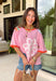 This pink floral top is full of those pretty little details that make summer outfits feel extra special! Featuring a colorful floral print with embroidered accents and white eyelet detailing, it has the perfect mix of texture and charm. The coral trim along the neckline and sleeves adds a fun pop of contrast that really makes it stand out. Lightweight and breathable in 100% cotton, it’s perfect for warm days when you want something easy but still eye-catching. 