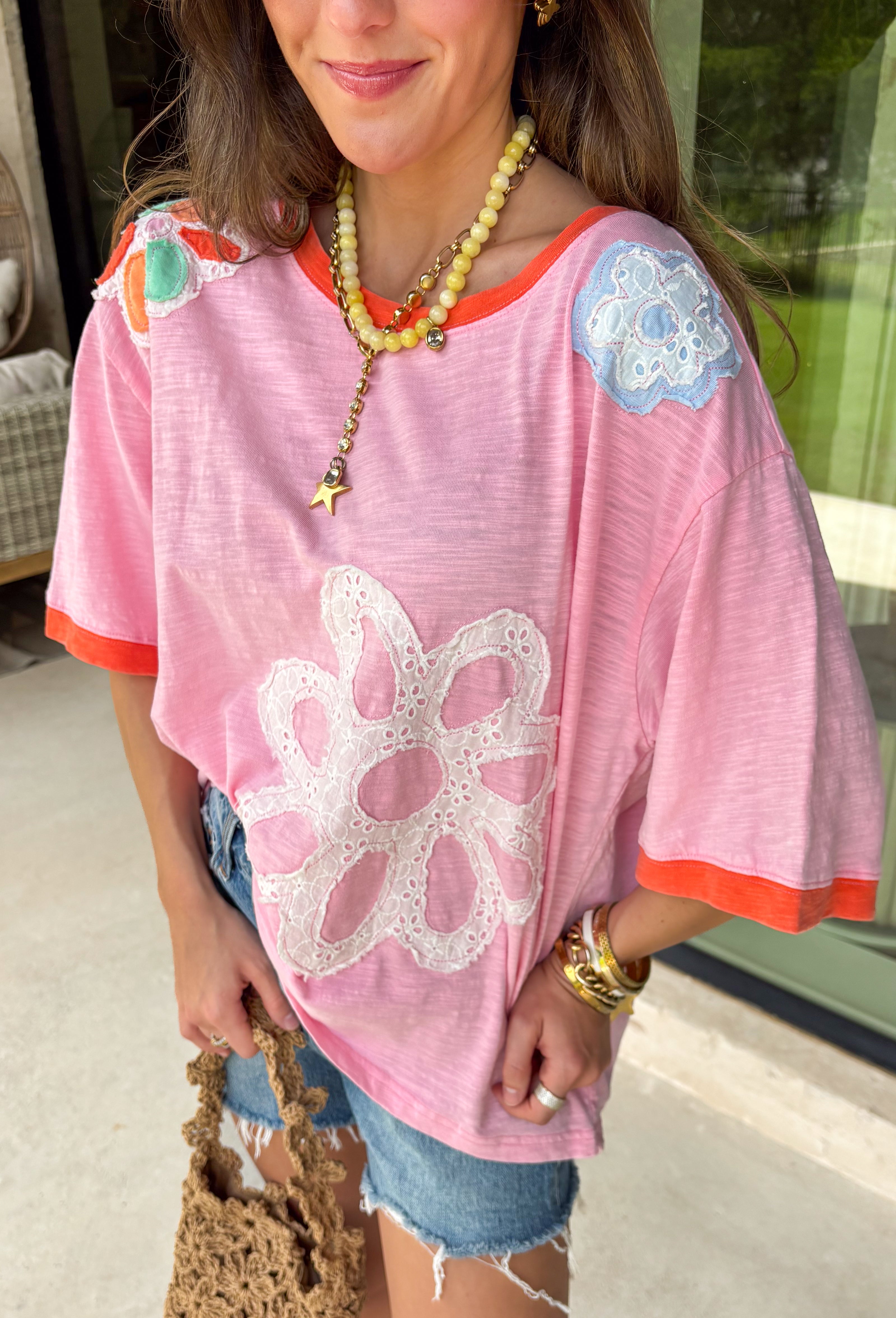 This pink floral top is full of those pretty little details that make summer outfits feel extra special! Featuring a colorful floral print with embroidered accents and white eyelet detailing, it has the perfect mix of texture and charm. The coral trim along the neckline and sleeves adds a fun pop of contrast that really makes it stand out. Lightweight and breathable in 100% cotton, it’s perfect for warm days when you want something easy but still eye-catching. 