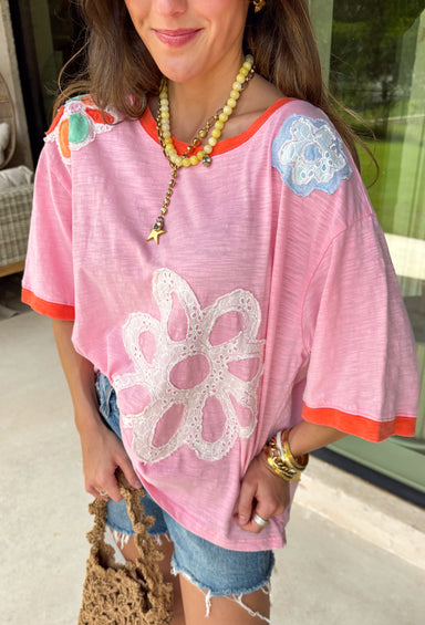 This pink floral top is full of those pretty little details that make summer outfits feel extra special! Featuring a colorful floral print with embroidered accents and white eyelet detailing, it has the perfect mix of texture and charm. The coral trim along the neckline and sleeves adds a fun pop of contrast that really makes it stand out. Lightweight and breathable in 100% cotton, it’s perfect for warm days when you want something easy but still eye-catching. 