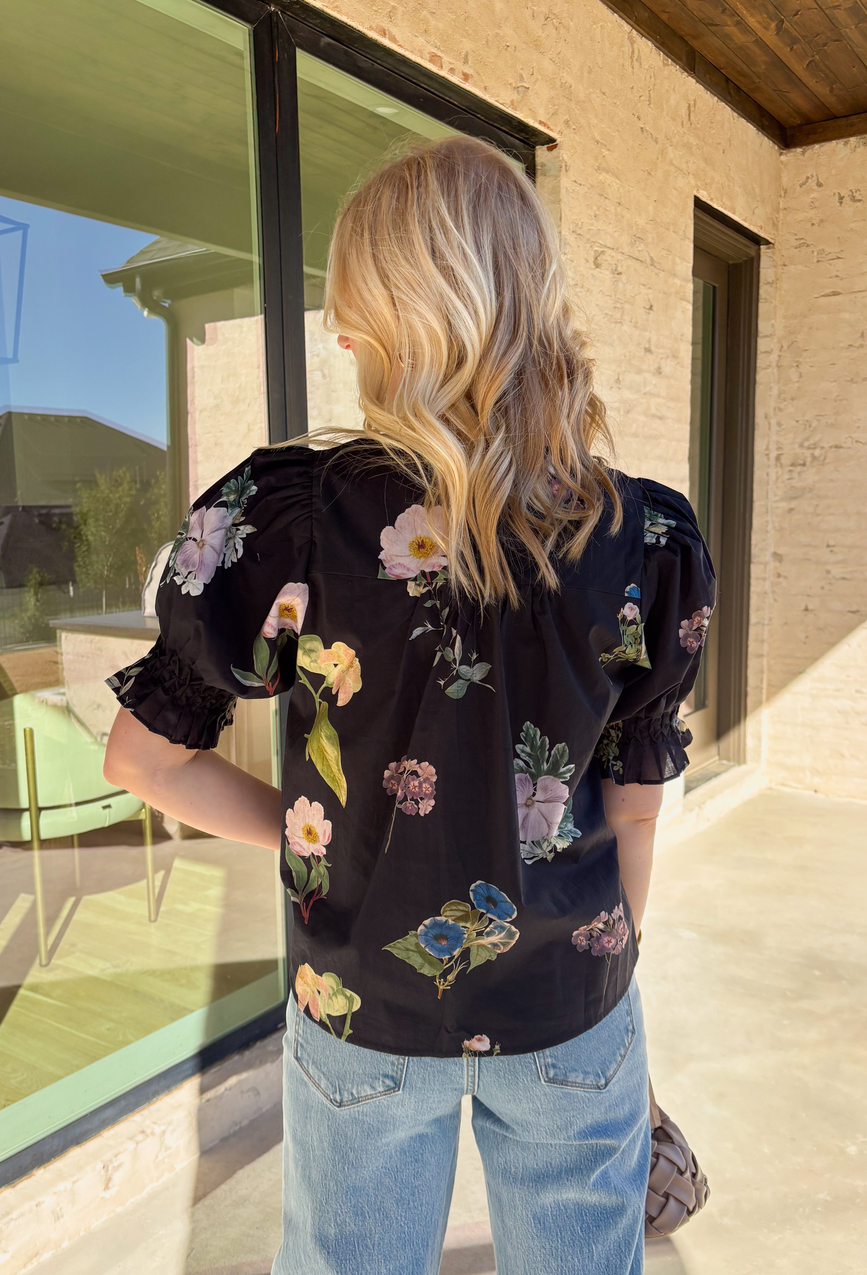 Classic with a spring refresh, this black short sleeve top by Entro is an easy standout. Featuring a soft floral print with pops of blush, green, and blue, it adds just the right amount of color to a timeless silhouette. The button-down front and pleating detail along the front give it a polished, flattering look, while the lightweight cotton fabric keeps it breathable and comfortable for warmer days.