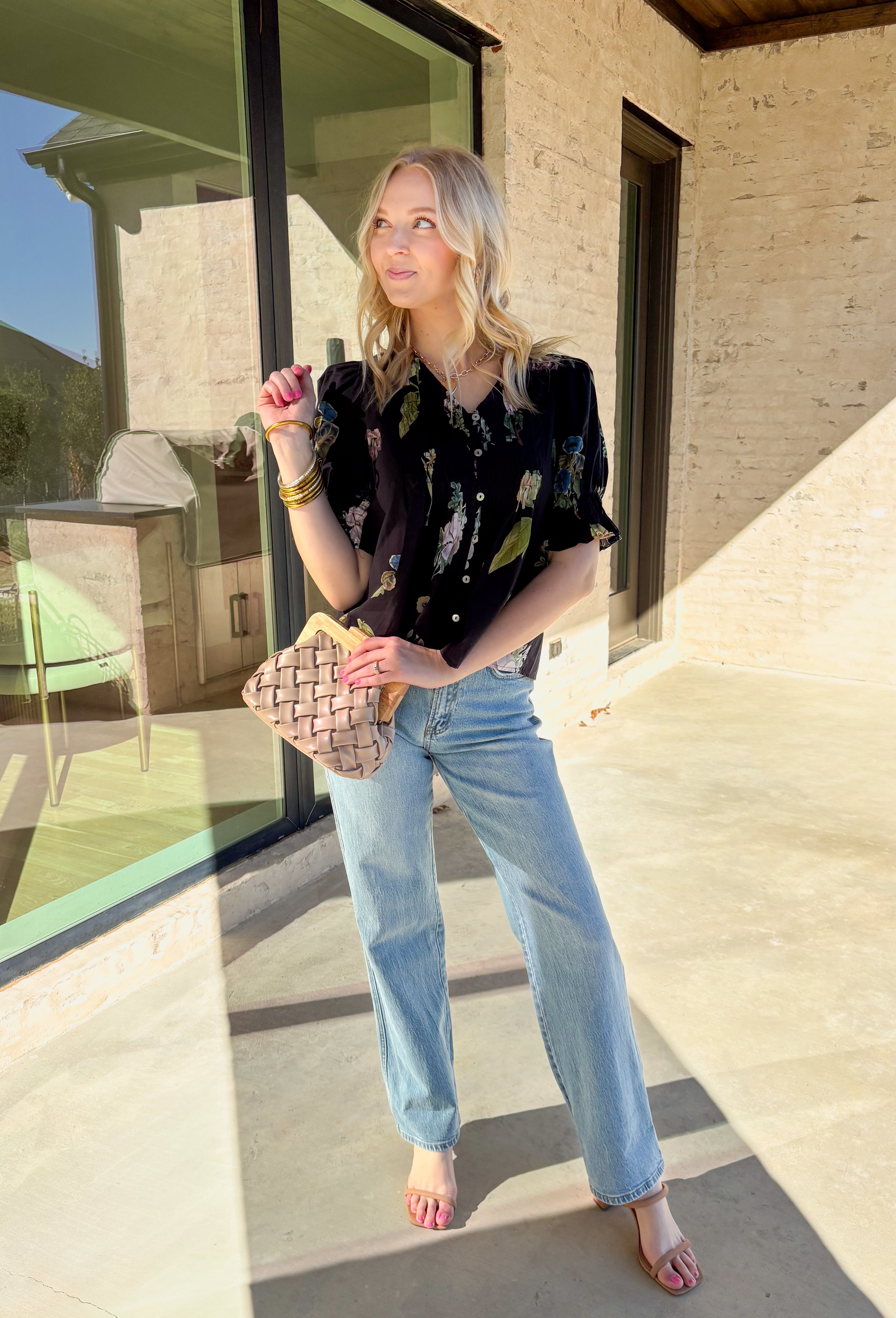 Classic with a spring refresh, this black short sleeve top by Entro is an easy standout. Featuring a soft floral print with pops of blush, green, and blue, it adds just the right amount of color to a timeless silhouette. The button-down front and pleating detail along the front give it a polished, flattering look, while the lightweight cotton fabric keeps it breathable and comfortable for warmer days.