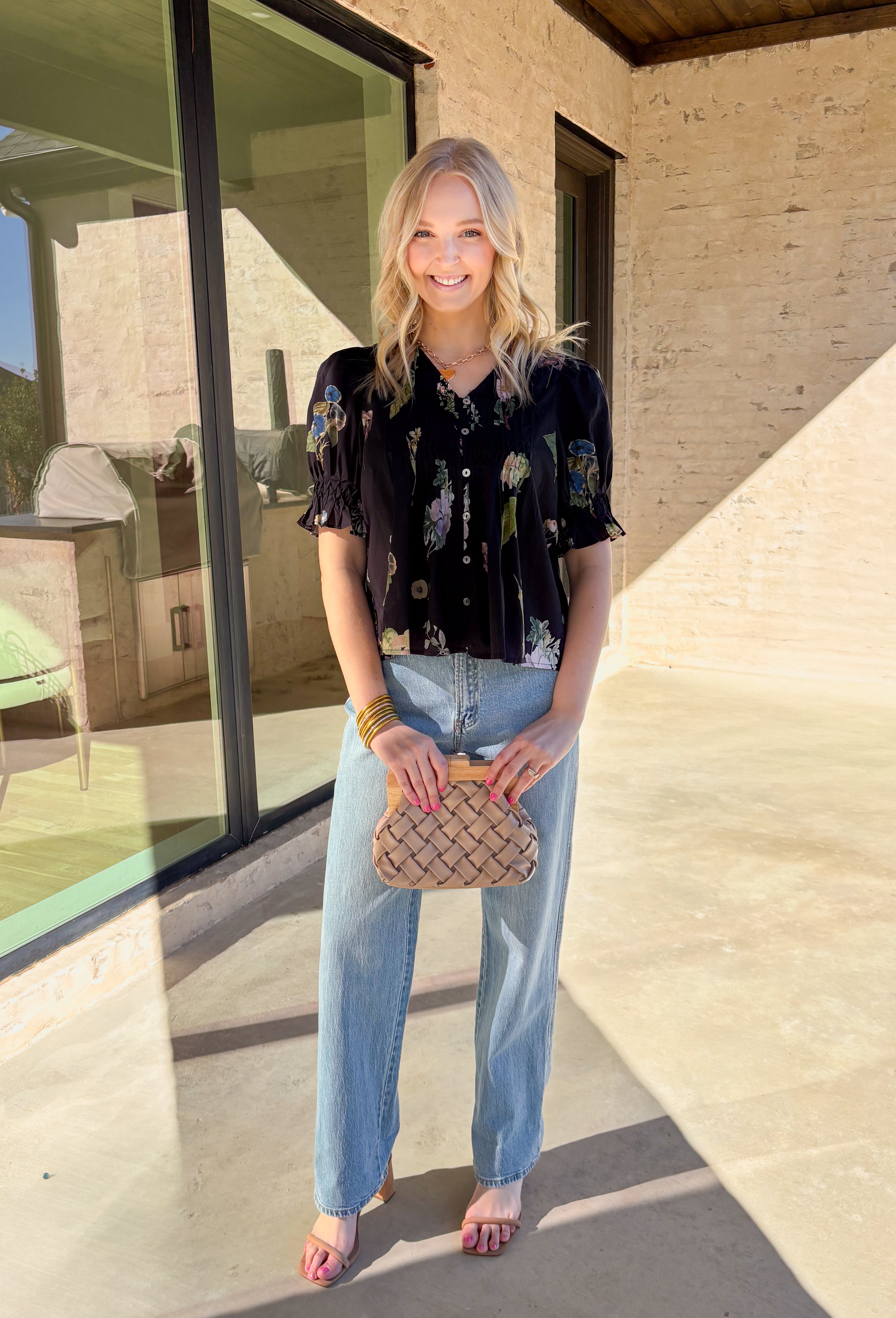 Classic with a spring refresh, this black short sleeve top by Entro is an easy standout. Featuring a soft floral print with pops of blush, green, and blue, it adds just the right amount of color to a timeless silhouette. The button-down front and pleating detail along the front give it a polished, flattering look, while the lightweight cotton fabric keeps it breathable and comfortable for warmer days.
