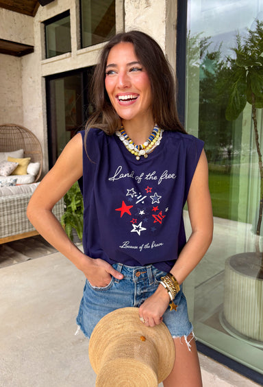 This navy graphic tank is made for celebrating summer and everything that comes with it! Featuring “Land Of The Free Because Of The Brave” with red, white, and blue star details, it brings the perfect patriotic touch for the 4th of July and beyond. The mix of printed and embroidered elements adds dimension and makes it feel extra special. Lightweight and breathable in 100% cotton, it’s perfect for warm days filled with BBQs, fireworks, and time with friends and family. 