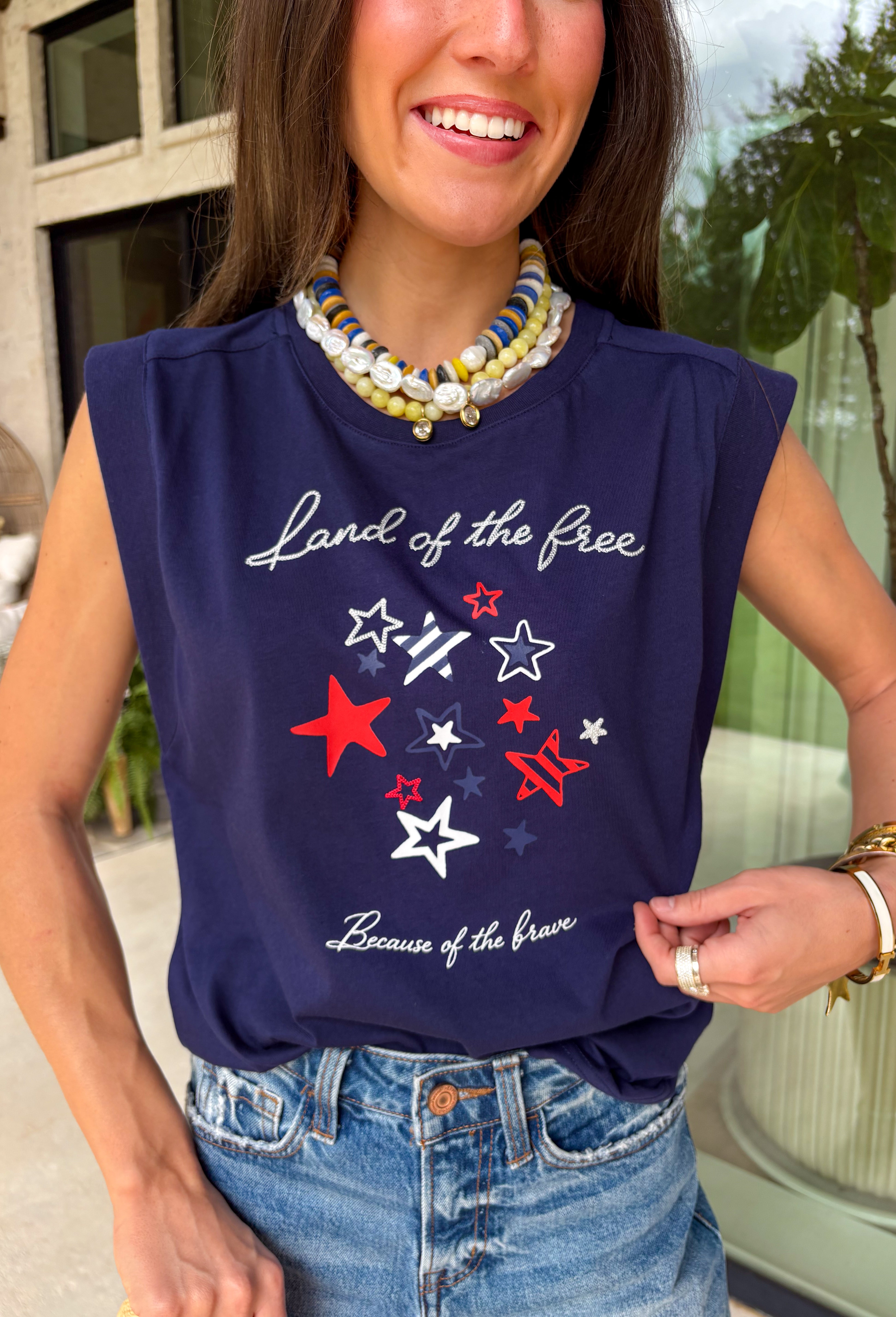 This navy graphic tank is made for celebrating summer and everything that comes with it! Featuring “Land Of The Free Because Of The Brave” with red, white, and blue star details, it brings the perfect patriotic touch for the 4th of July and beyond. The mix of printed and embroidered elements adds dimension and makes it feel extra special. Lightweight and breathable in 100% cotton, it’s perfect for warm days filled with BBQs, fireworks, and time with friends and family. 