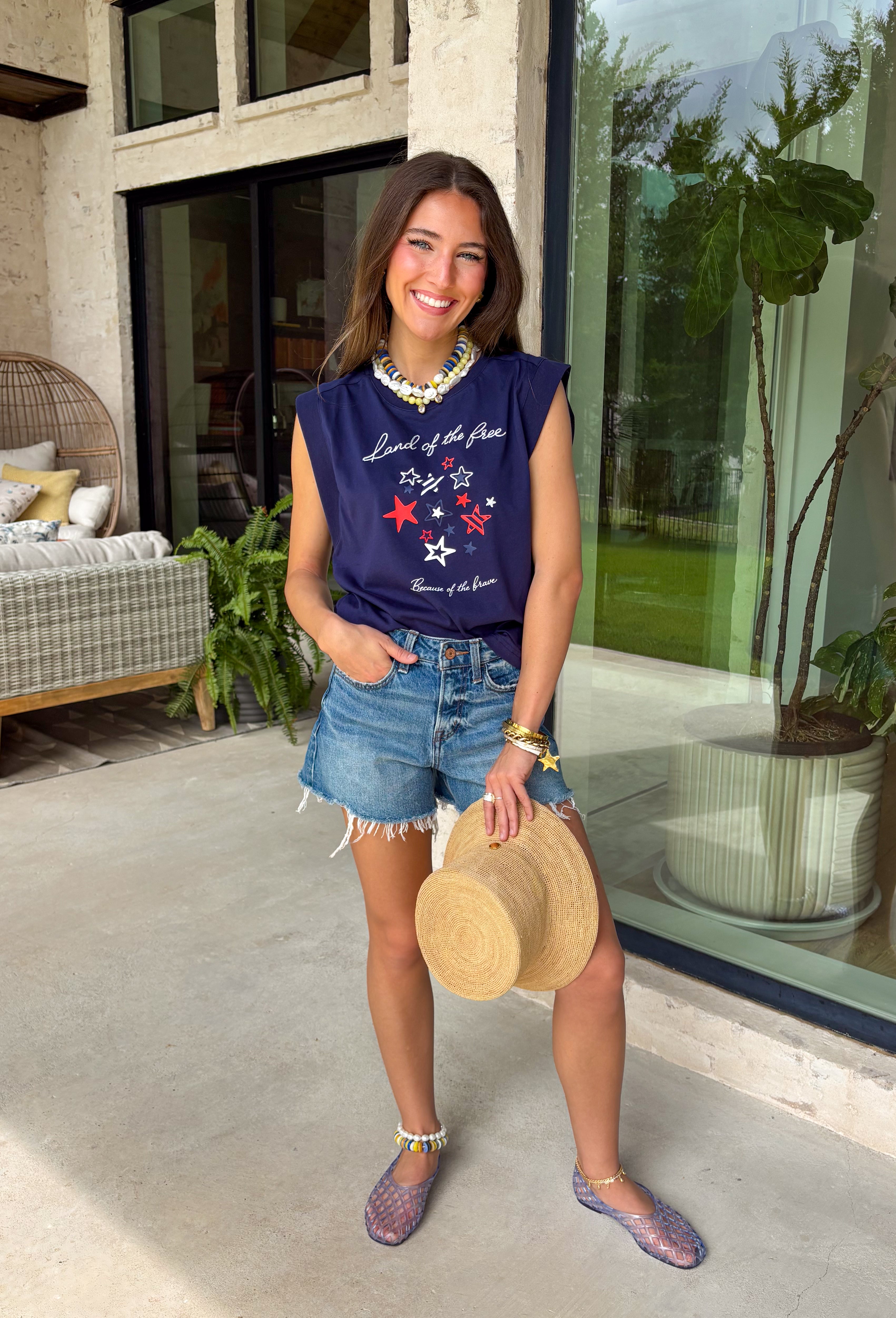 This navy graphic tank is made for celebrating summer and everything that comes with it! Featuring “Land Of The Free Because Of The Brave” with red, white, and blue star details, it brings the perfect patriotic touch for the 4th of July and beyond. The mix of printed and embroidered elements adds dimension and makes it feel extra special. Lightweight and breathable in 100% cotton, it’s perfect for warm days filled with BBQs, fireworks, and time with friends and family. 