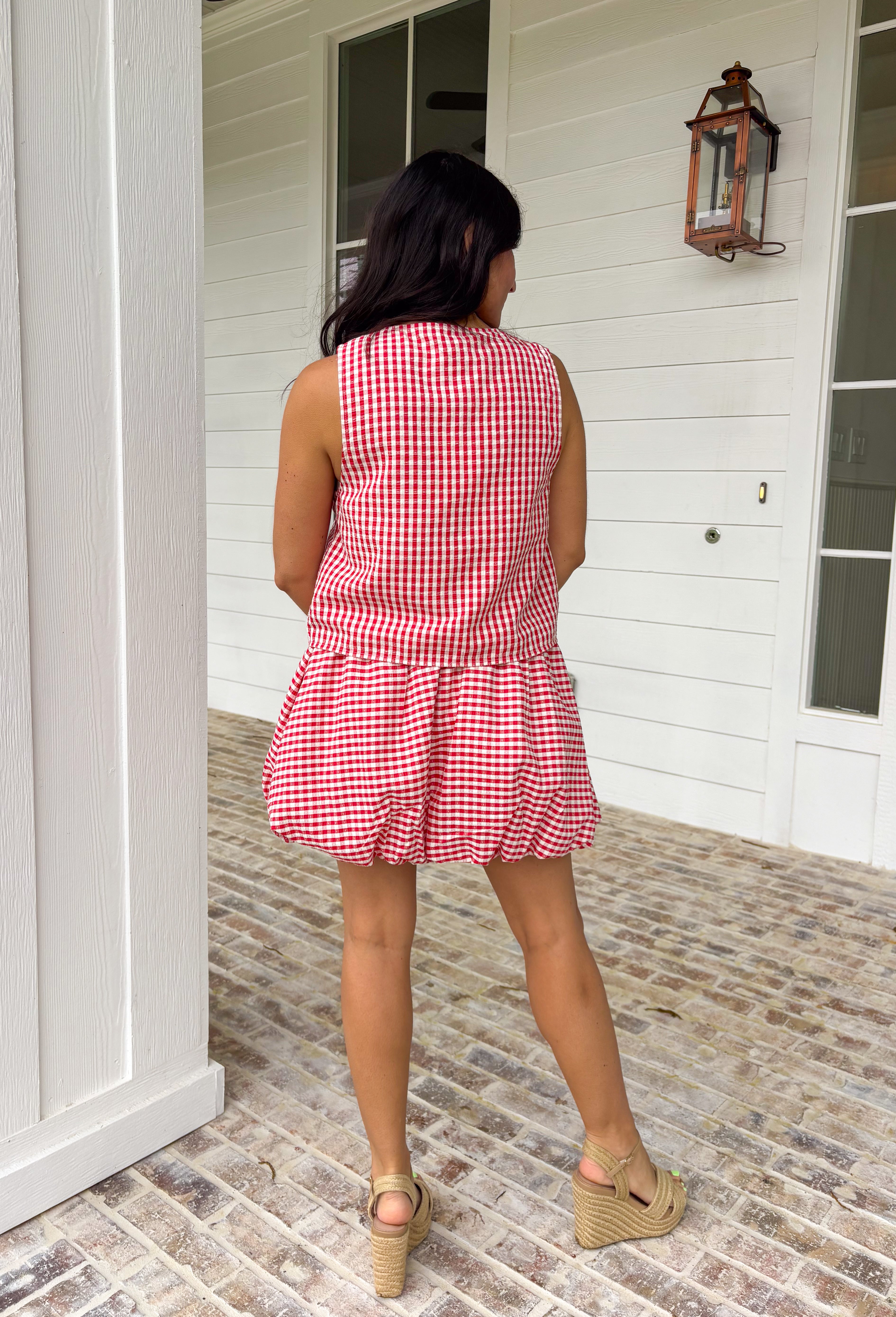 Nothing says sunny days and sweet summertime like a classic red and white gingham print. This sleeveless button down top is equal parts timeless and playful, making it a go-to for backyard barbecues, lake weekends, and especially the 4th of July. The crisp gingham pattern gives it that all-American charm, while the lightweight feel keeps it easy and comfortable all day long. Wear it with the matching skirt for an effortlessly coordinated set.