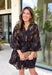 Step into the season with effortless style in this beautifully detailed dress from Entro. Designed with a classic black backdrop and a rich floral print in shades of brown and tan, this timeless dress captures the warmth of fall with every detail. The flattering v-neckline and button-front design create a polished silhouette, while the included matching belt defines the waist for a customizable fit. Finished with ¾ balloon sleeves, a playful ruffle hem, convenient side pockets.
